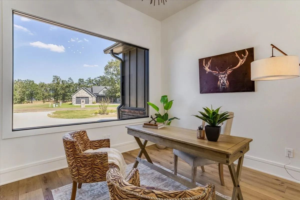 Expansive floor-to-ceiling window with black trim, wood-finish flooring, and crisp white walls