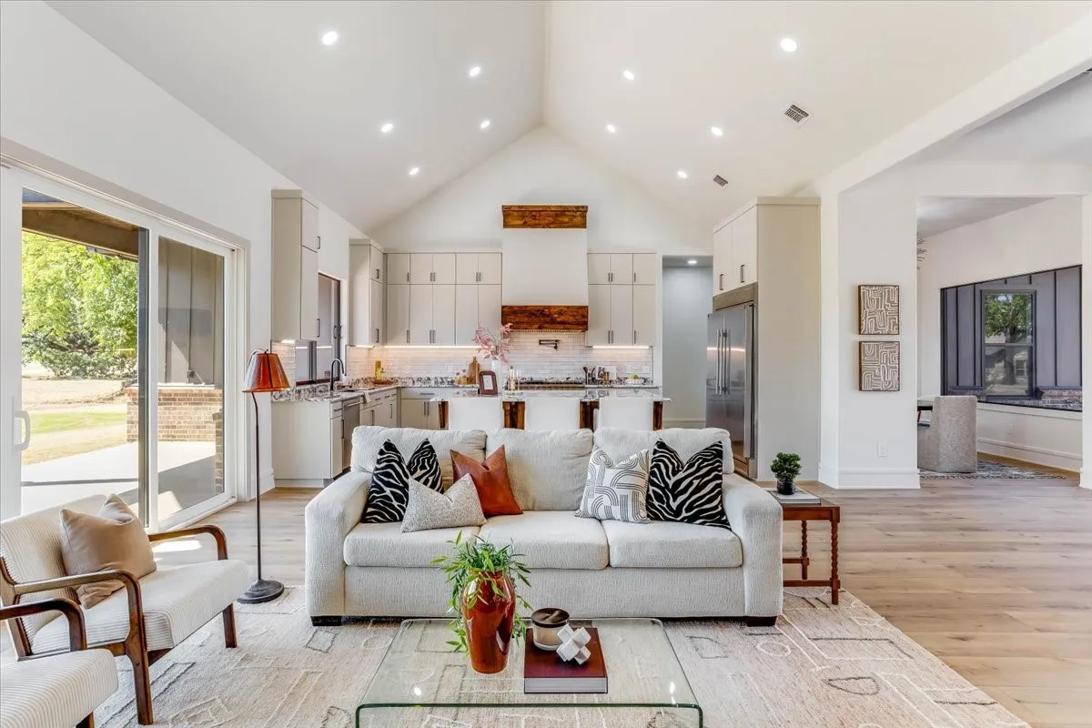 Vaulted ceiling with recessed lighting, wood-finish flooring, kitchen with built-in cabinetry, stainless steel appliances, and a sliding glass door leading to the exterior