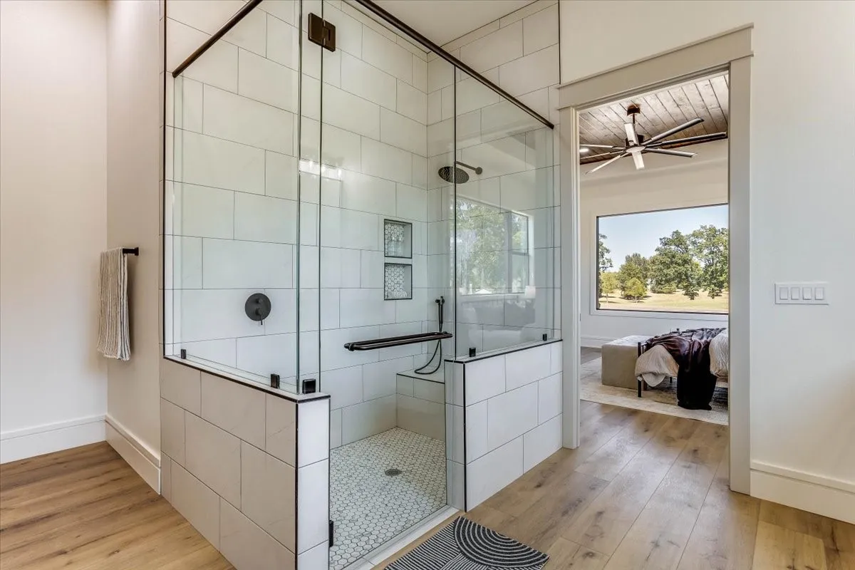 Glass-enclosed shower with white subway tile, built-in bench, and rain showerhead