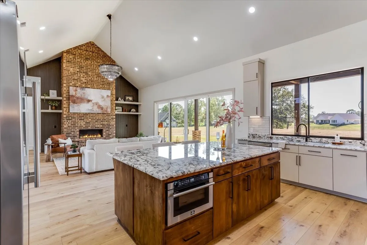 Spacious kitchen with a central island featuring a built-in microwave, light wood-finish flooring, and white cabinetry