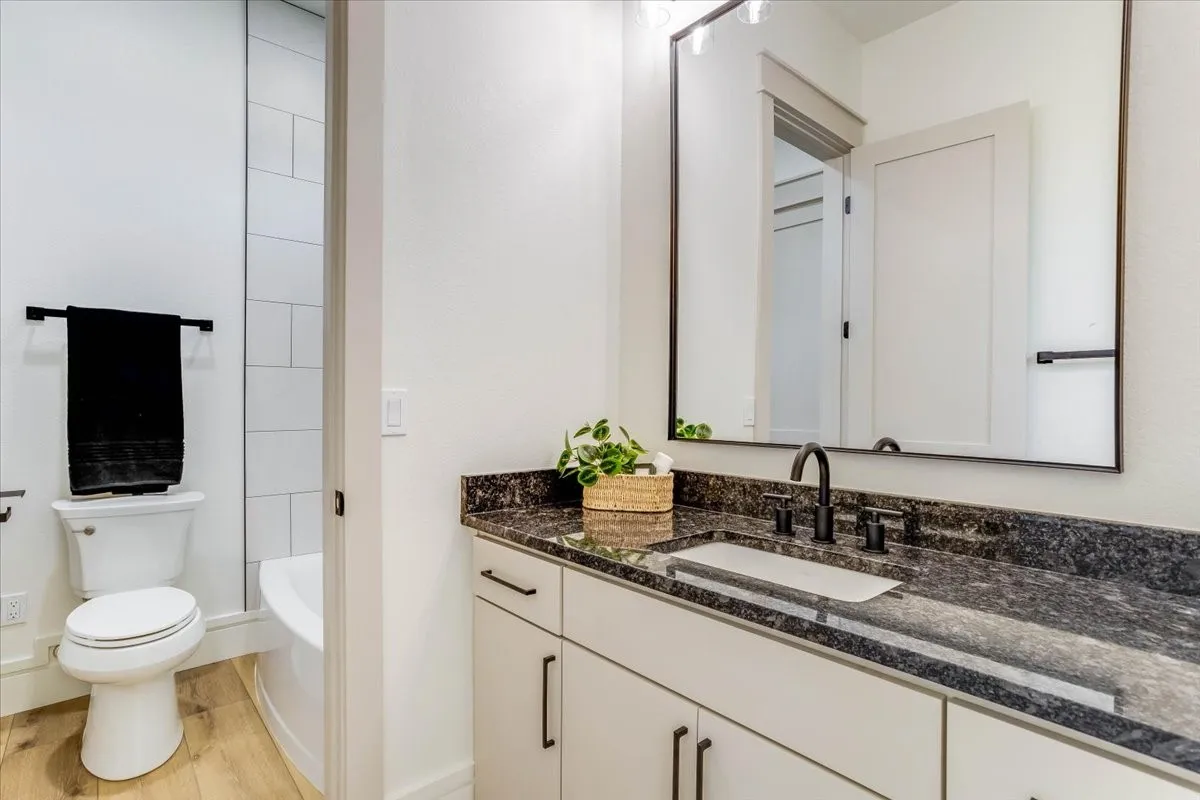 White vanity with dark granite countertop, undermount rectangular sink, and matte black fixtures
