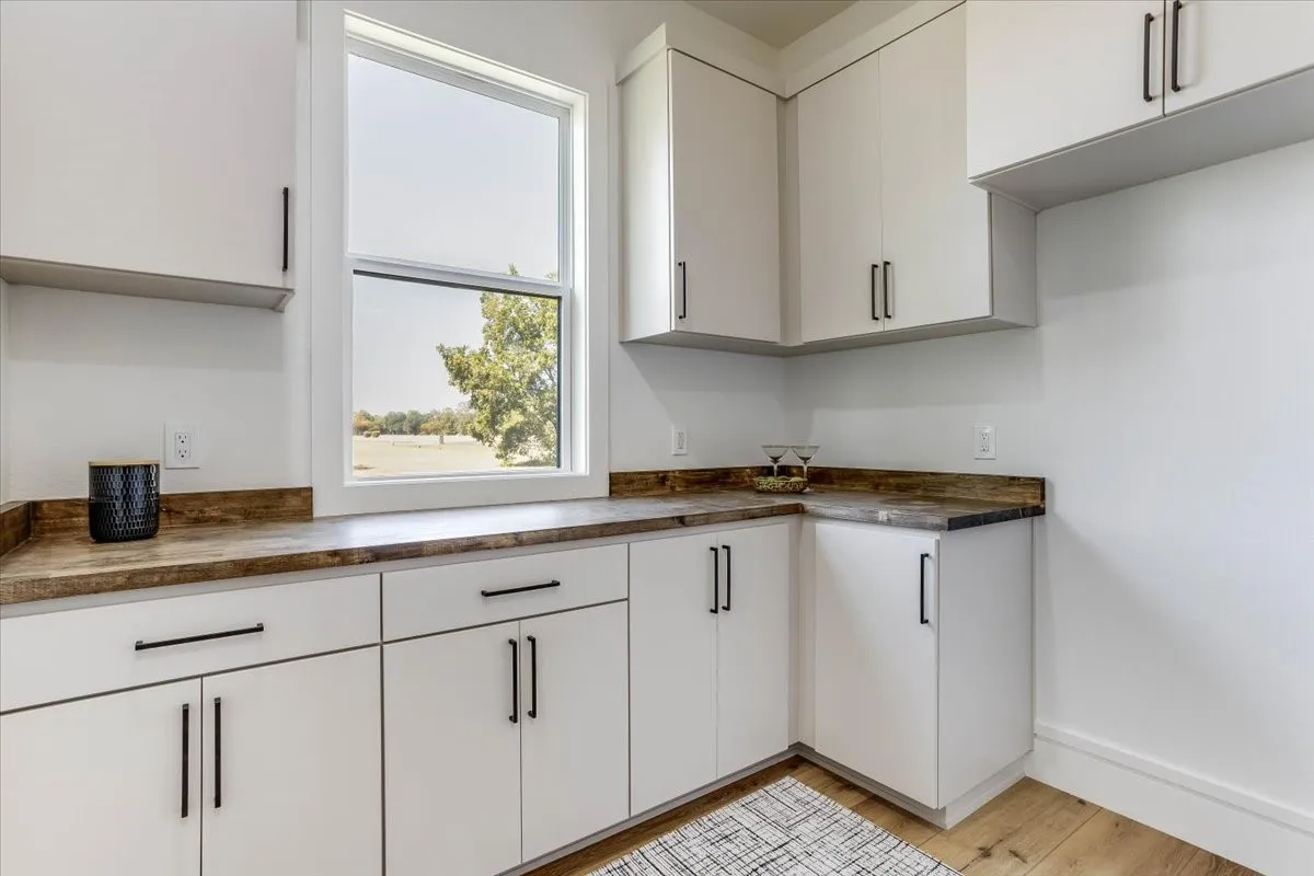 White cabinetry with matte black hardware, wood-finish countertops, and LVP flooring