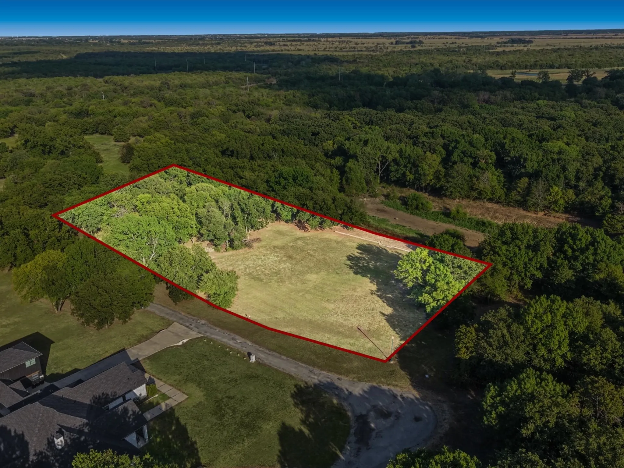 Expansive land parcel featuring a mix of cleared areas and mature trees
