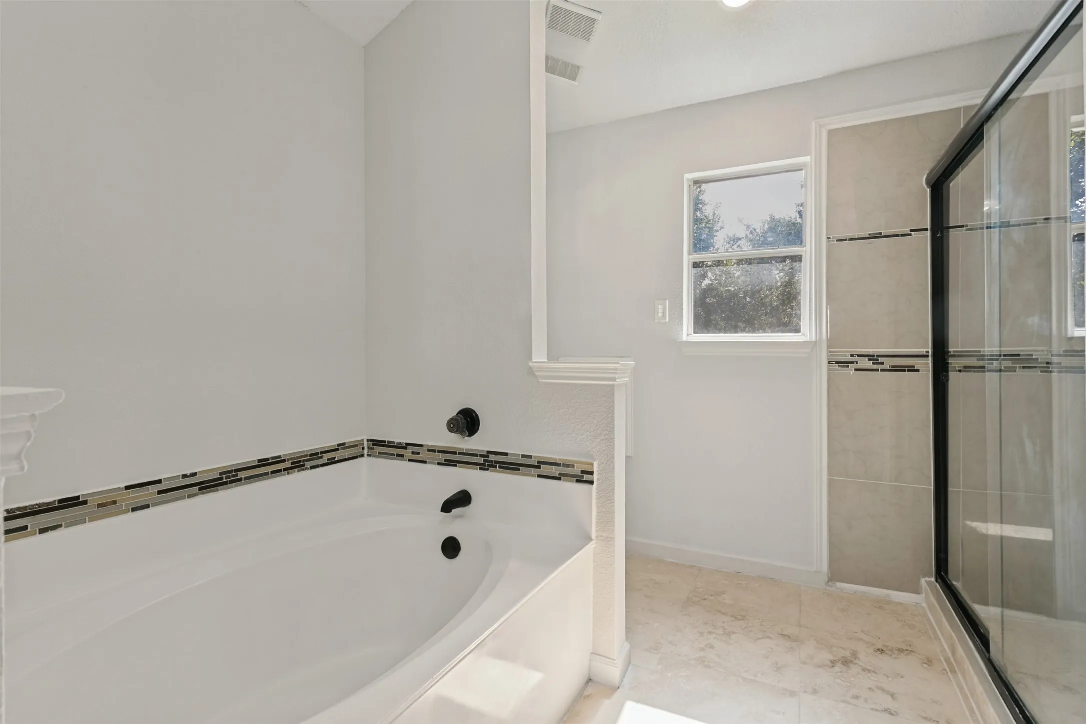 Built-in soaking tub with decorative tile surround and dark bronze fixtures