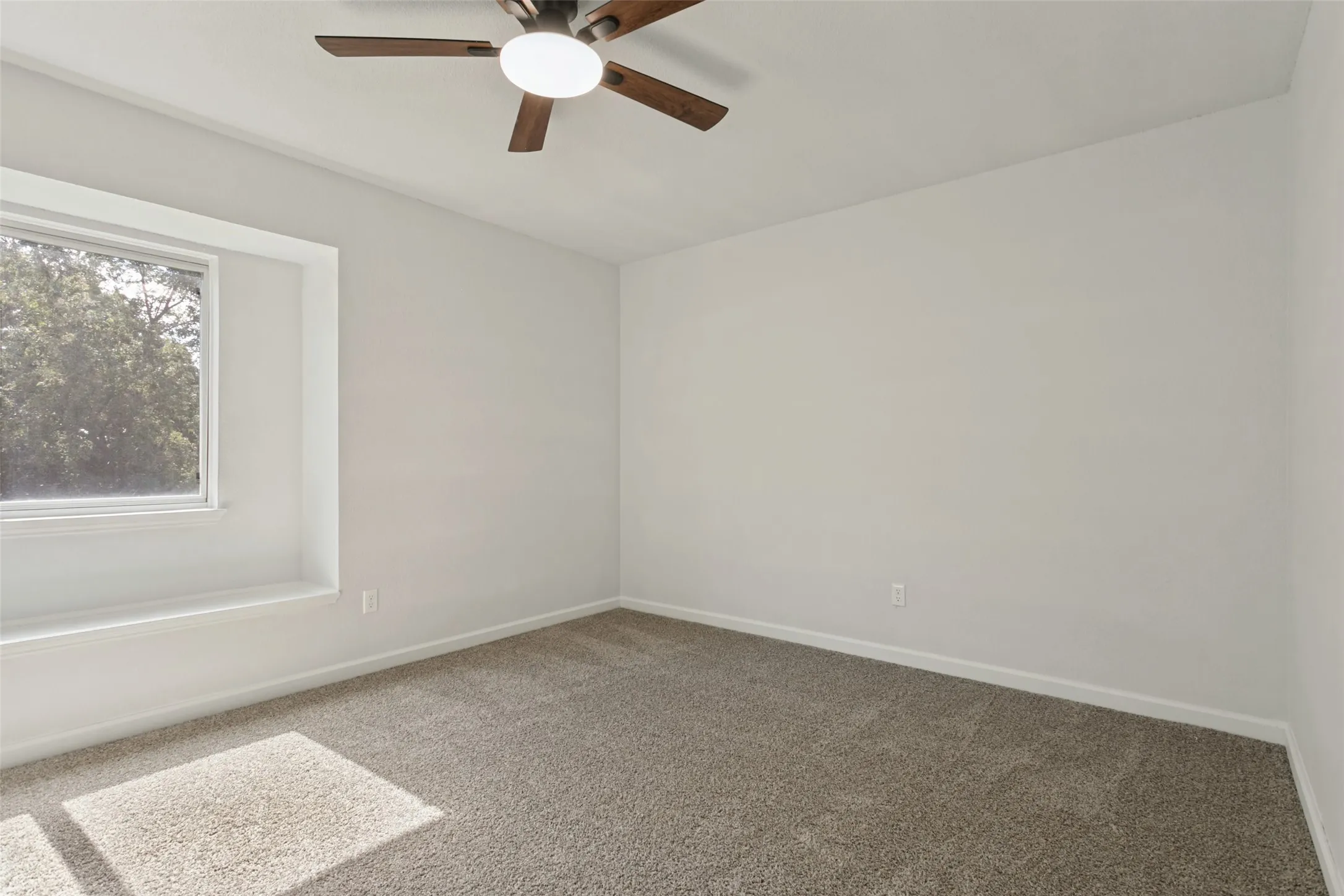 Room featuring a ceiling fan with integrated lighting, a window with a recessed sill, and neutral-toned carpeting