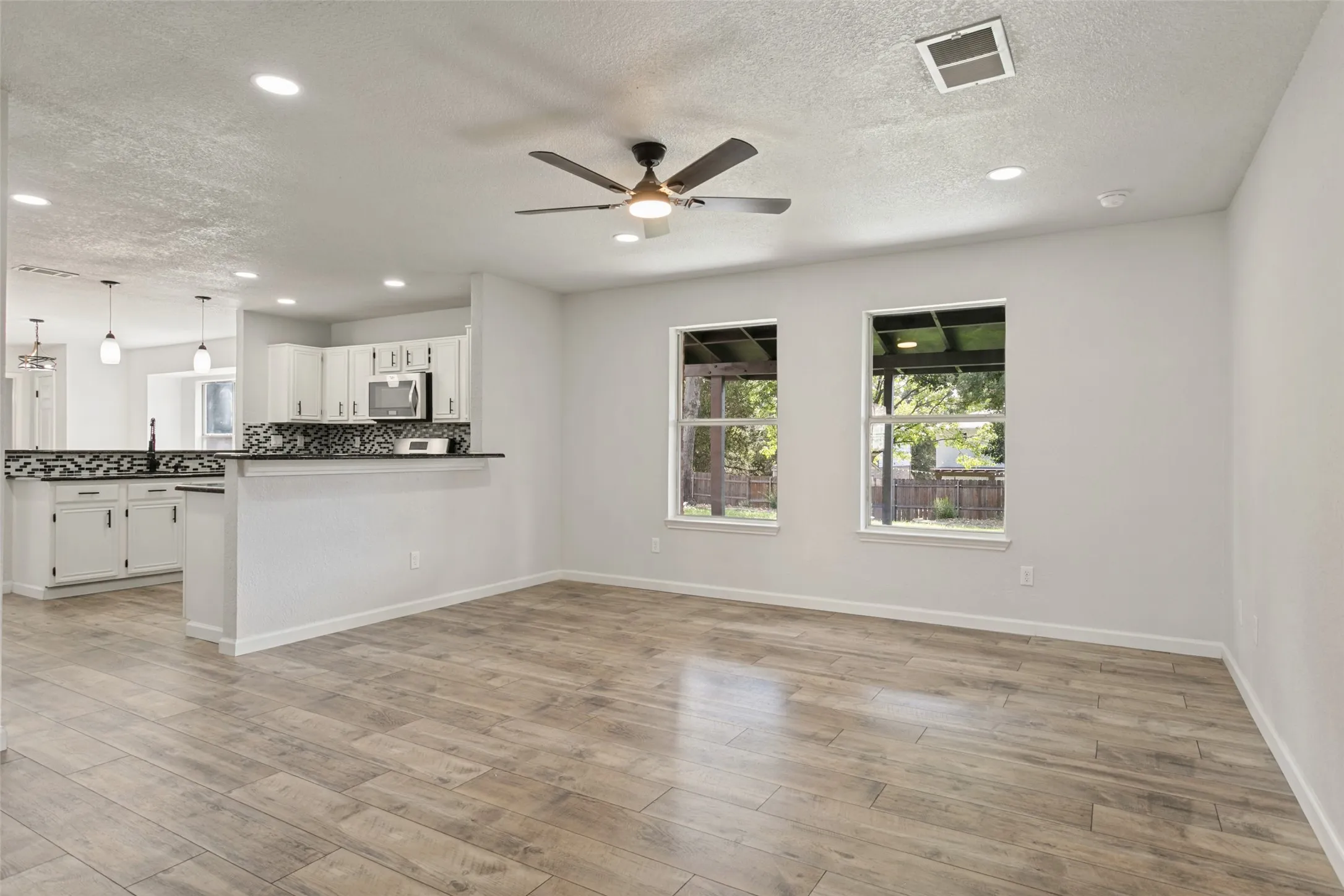 Open-concept living area featuring wood-finish flooring, recessed lighting, and a ceiling fan