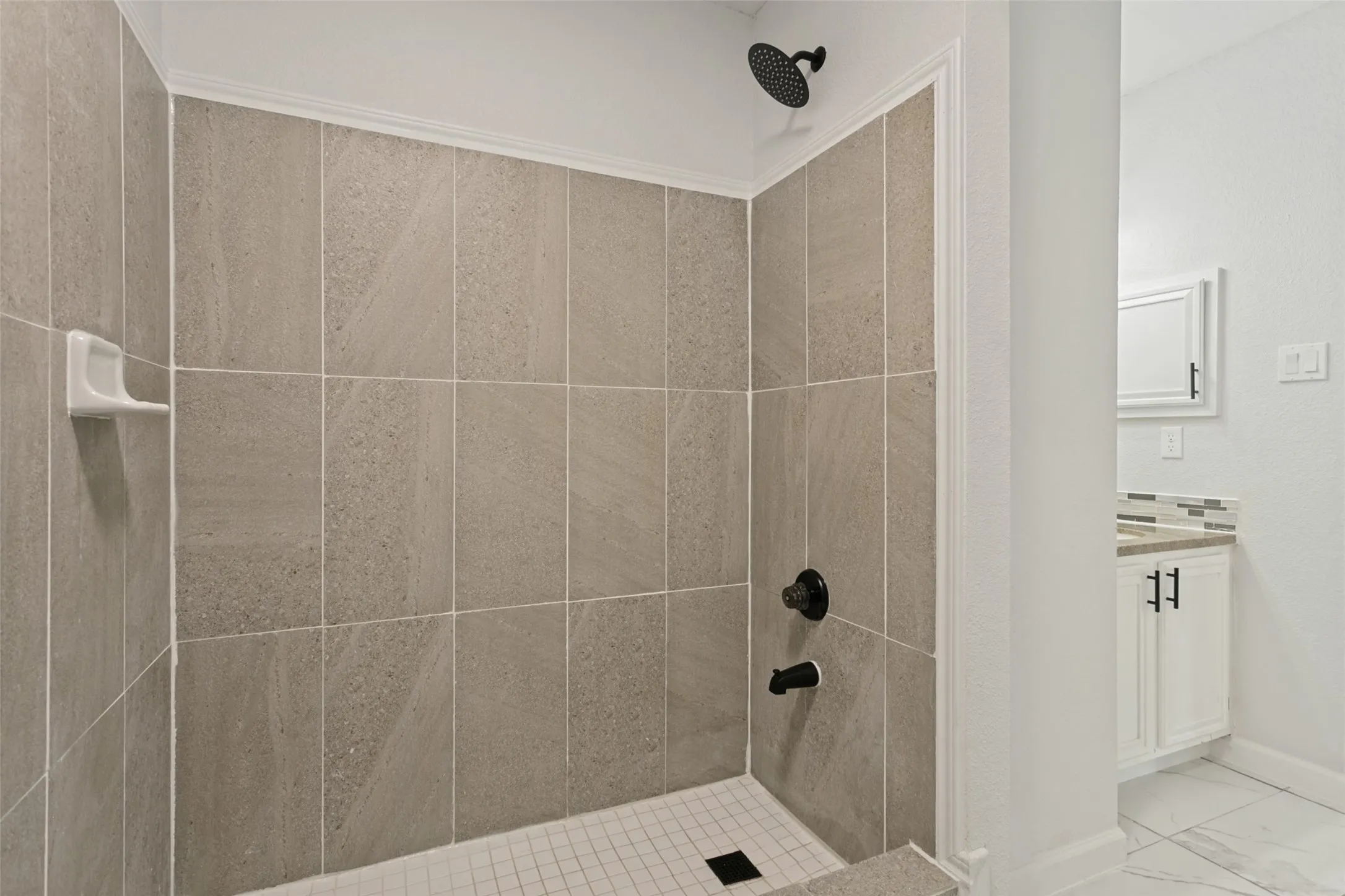 Tiled shower with a rainfall showerhead, black fixtures, and a low-profile threshold