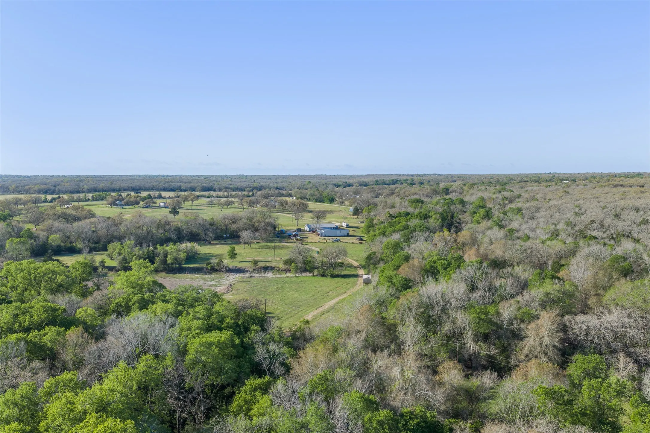 Expansive natural landscape featuring lush greenery, mature trees, and open clearings