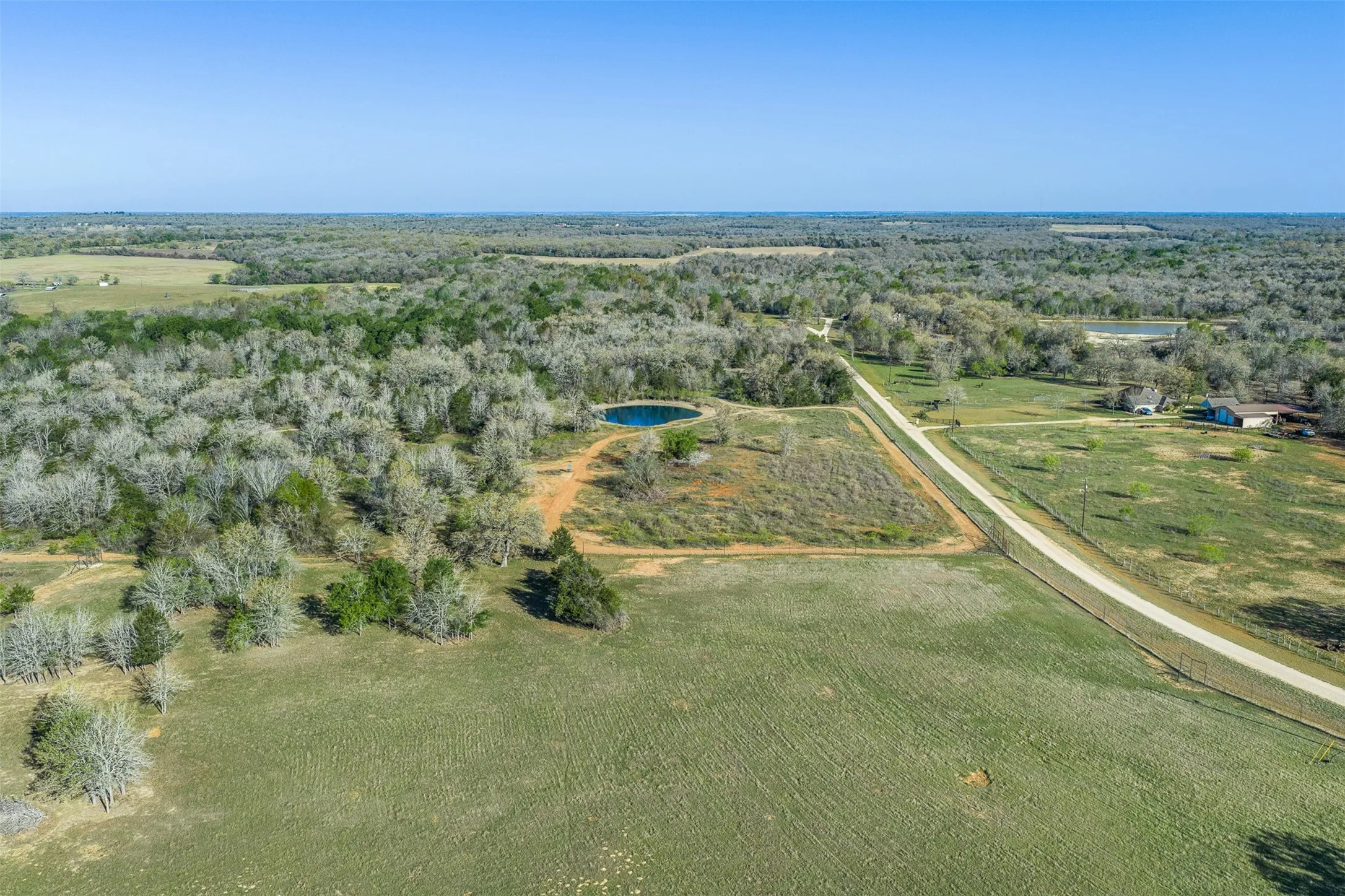 Expansive acreage featuring a private pond, open fields, and wooded areas