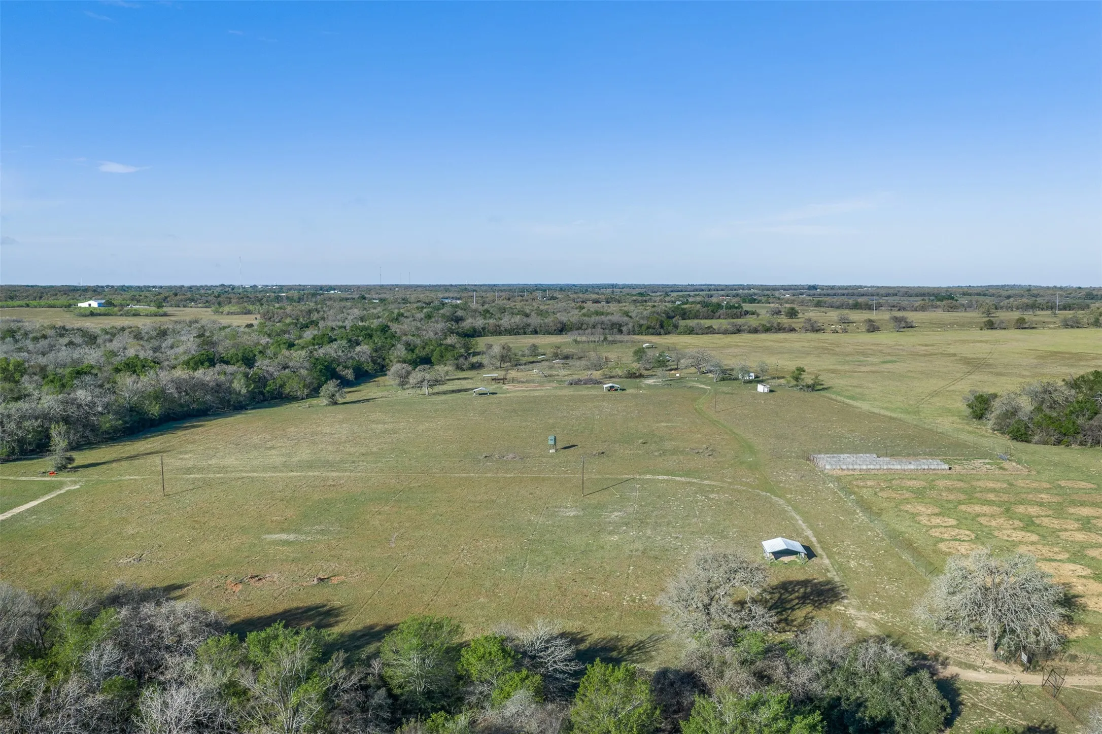 Expansive property featuring vast open fields, scattered mature trees, and multiple outbuildings