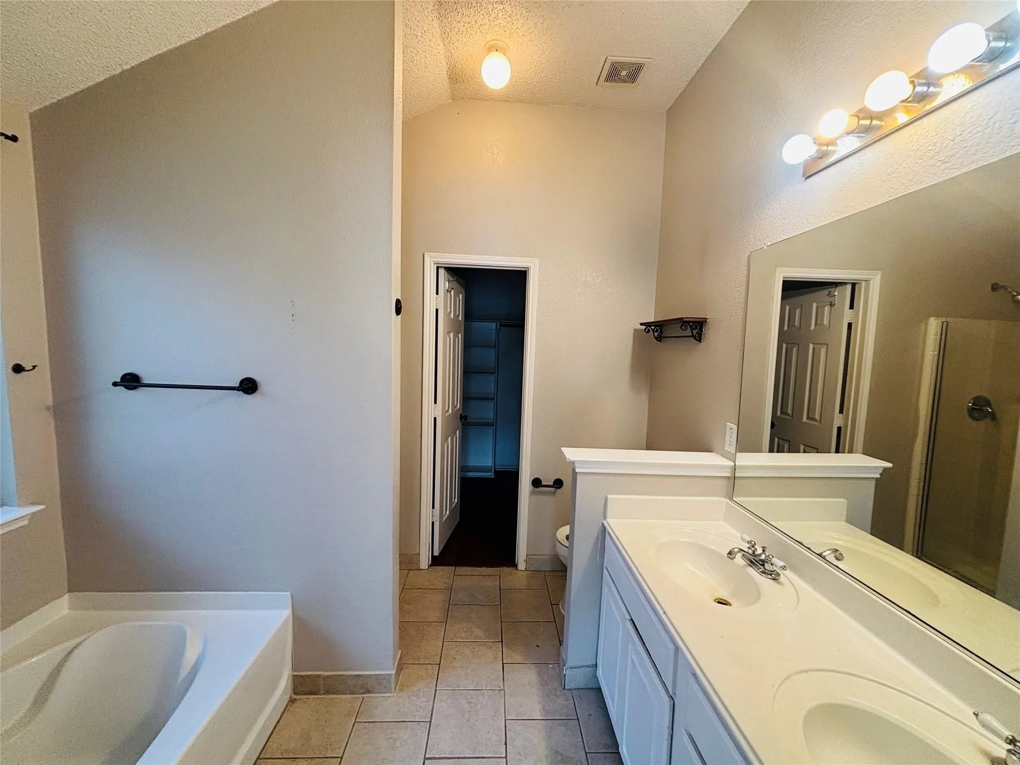 Dual vanity with integrated sinks, tiled flooring, an enclosed shower, and a built-in bathtub