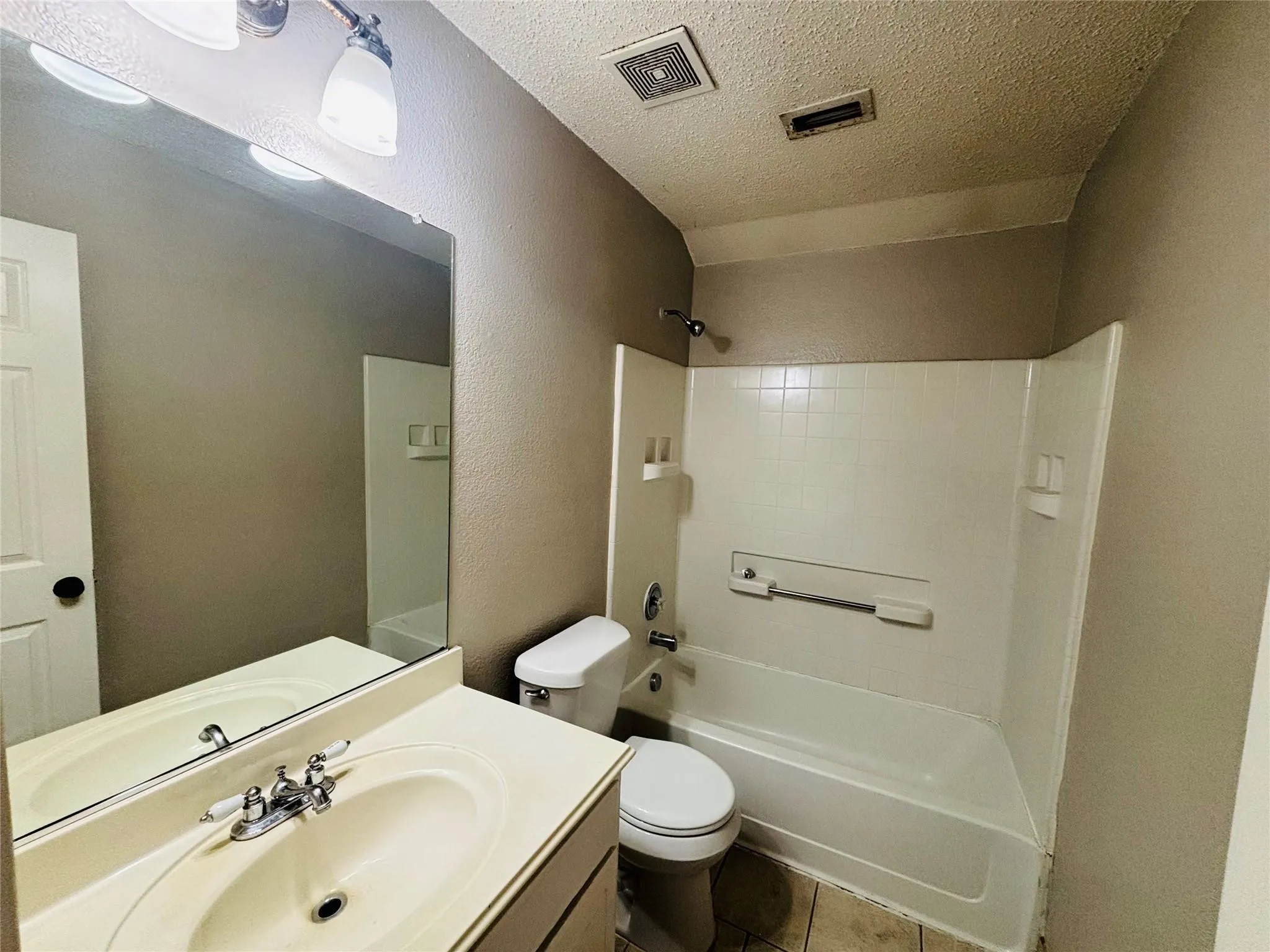 Bathroom featuring a vanity with an integrated sink, polished chrome faucet, full-width mirror, and a white tub/shower combination with a tiled surround