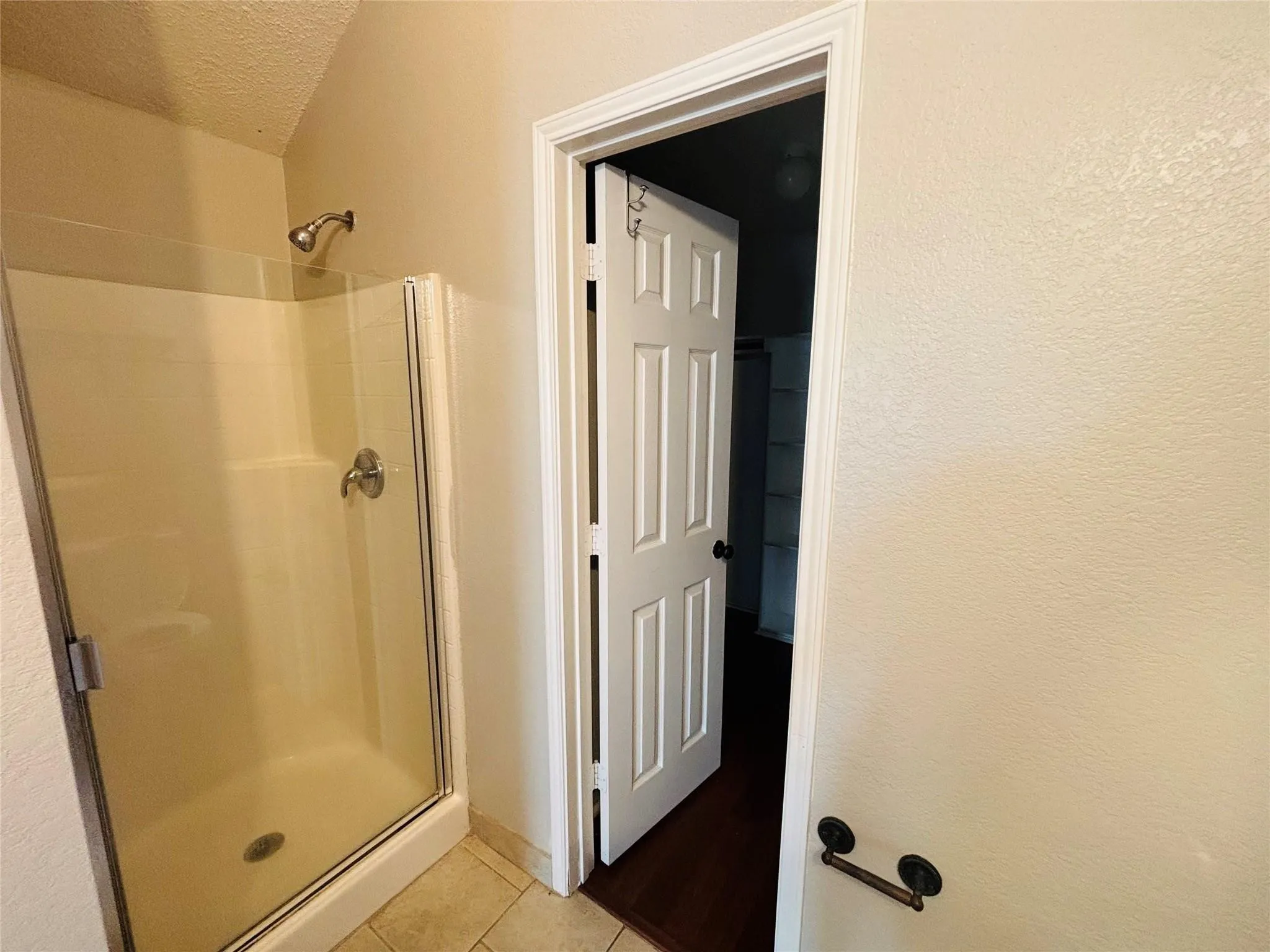 Enclosed shower with glass panel, brushed nickel fixtures, and tiled flooring
