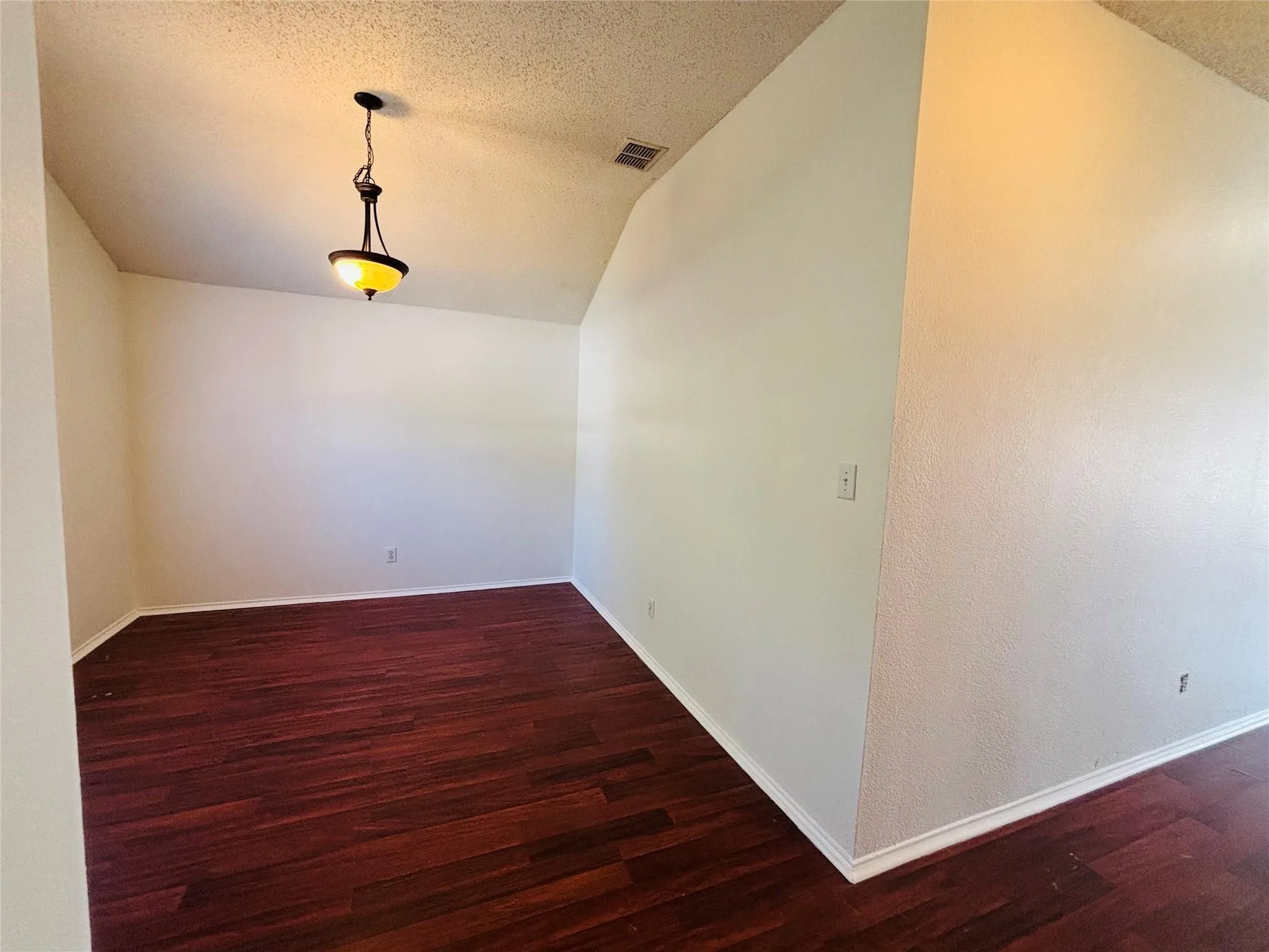 Wood-finish flooring with baseboard molding and a decorative pendant light fixture