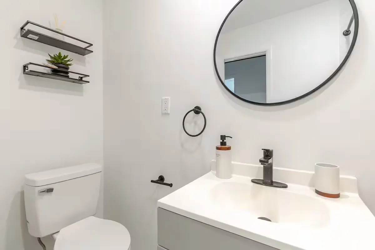 White vanity with an integrated sink and matte black faucet, paired with a circular mirror