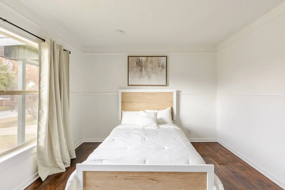 Dark wood-finish flooring, white walls with wainscoting, crown molding, and a large window