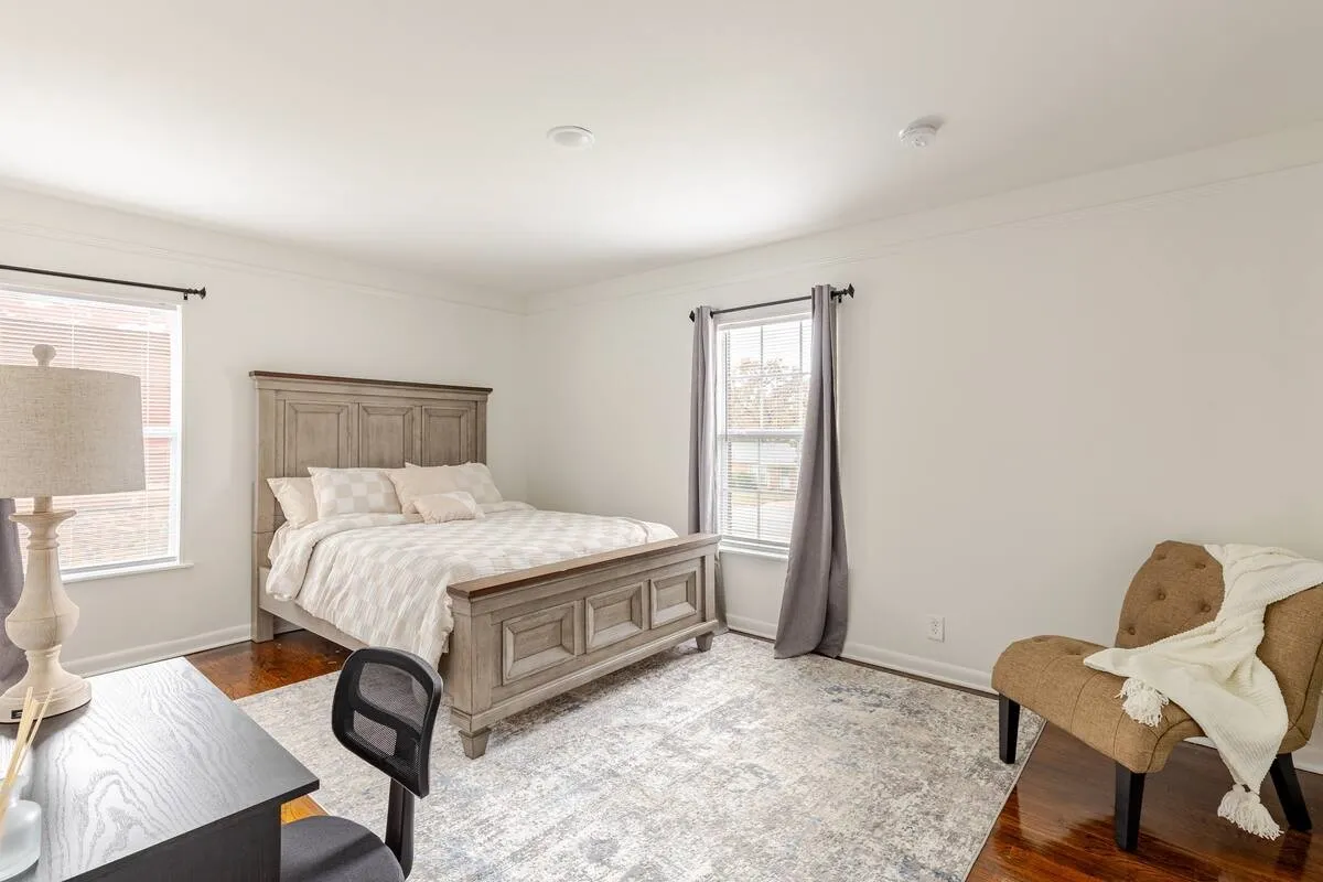 Hardwood flooring paired with crown molding, two windows with window treatments, and recessed lighting
