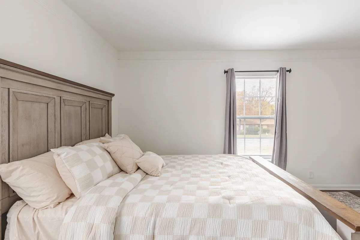 Crisp white walls with crown molding, a window with horizontal blinds, and wood-finish flooring