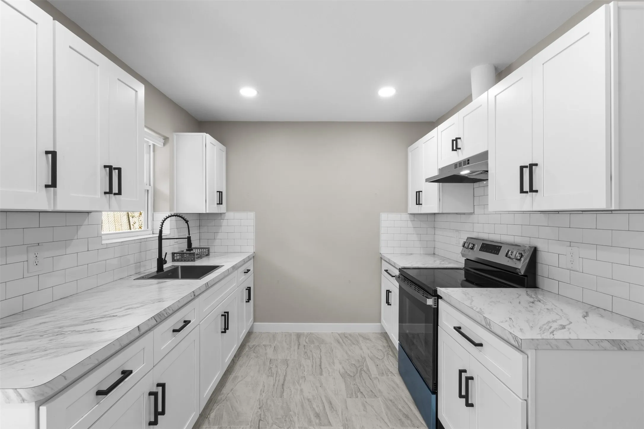 White shaker cabinetry, black hardware, white subway tile backsplash, light-toned countertops, and integrated recessed lighting