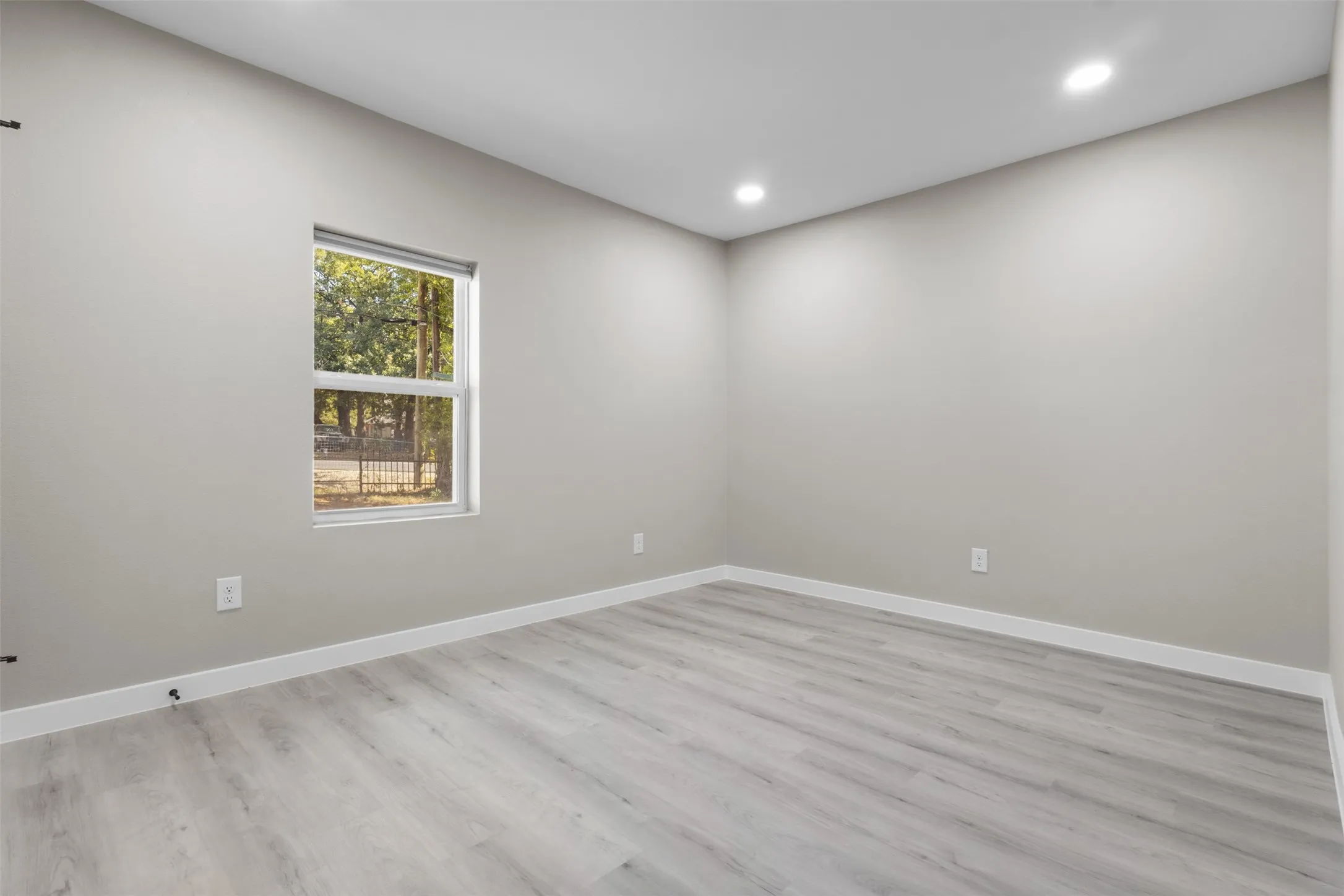 Light-toned walls, recessed ceiling lighting, light wood-finish flooring, and white trim