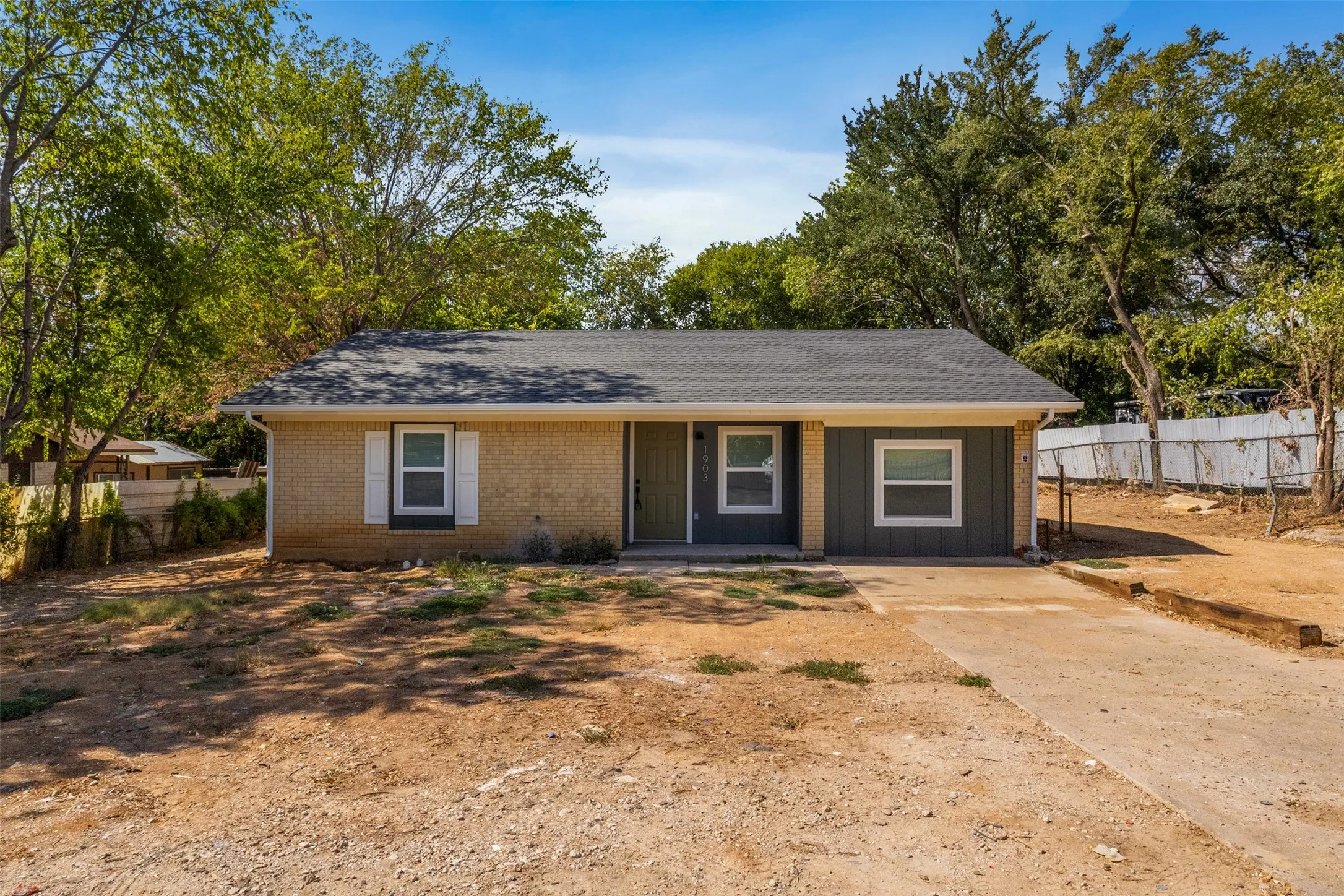 Single-story residence featuring a gray shingled roof, a front door, and a concrete driveway