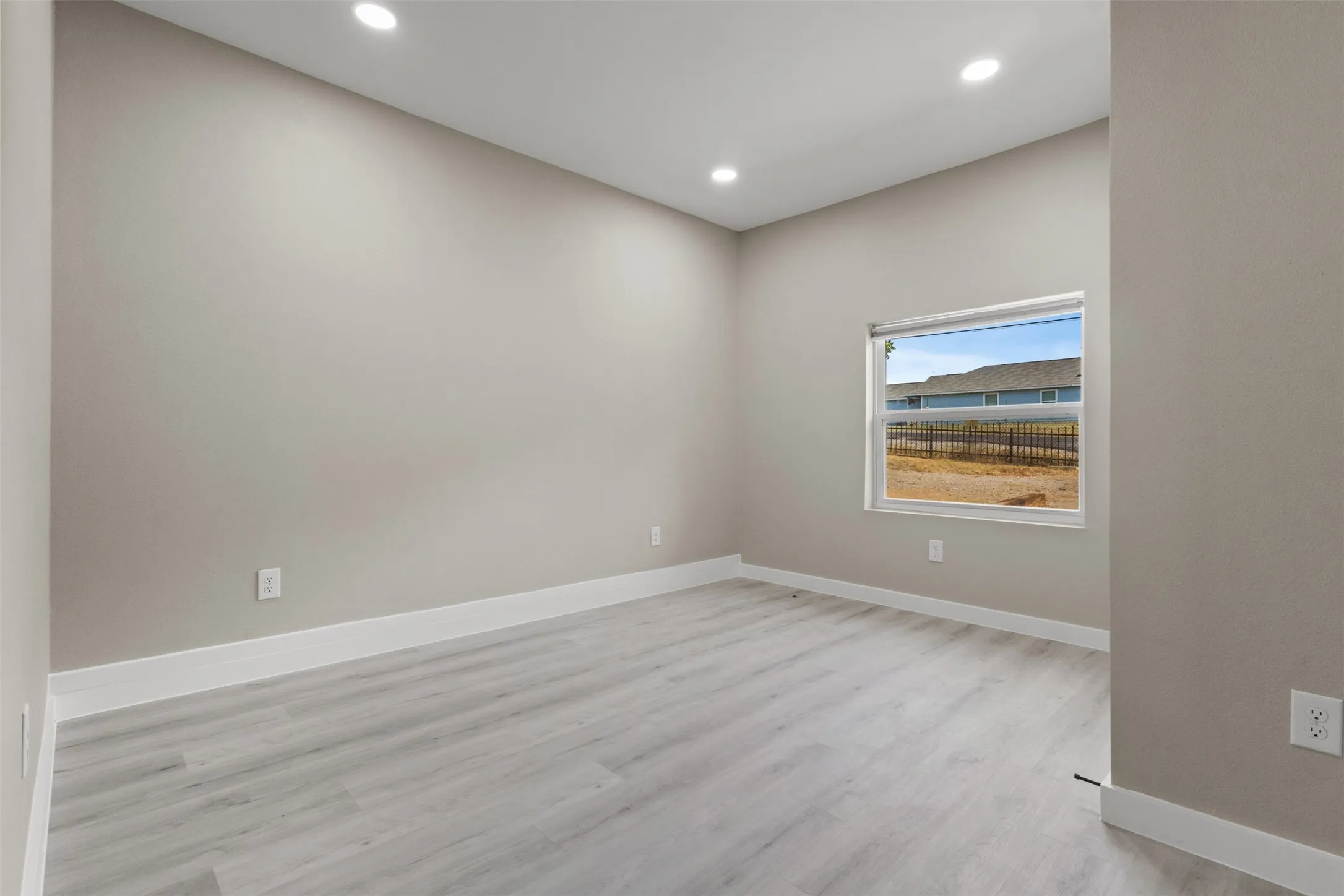 Recessed lighting, light-toned walls, wood-finish flooring, and a single window