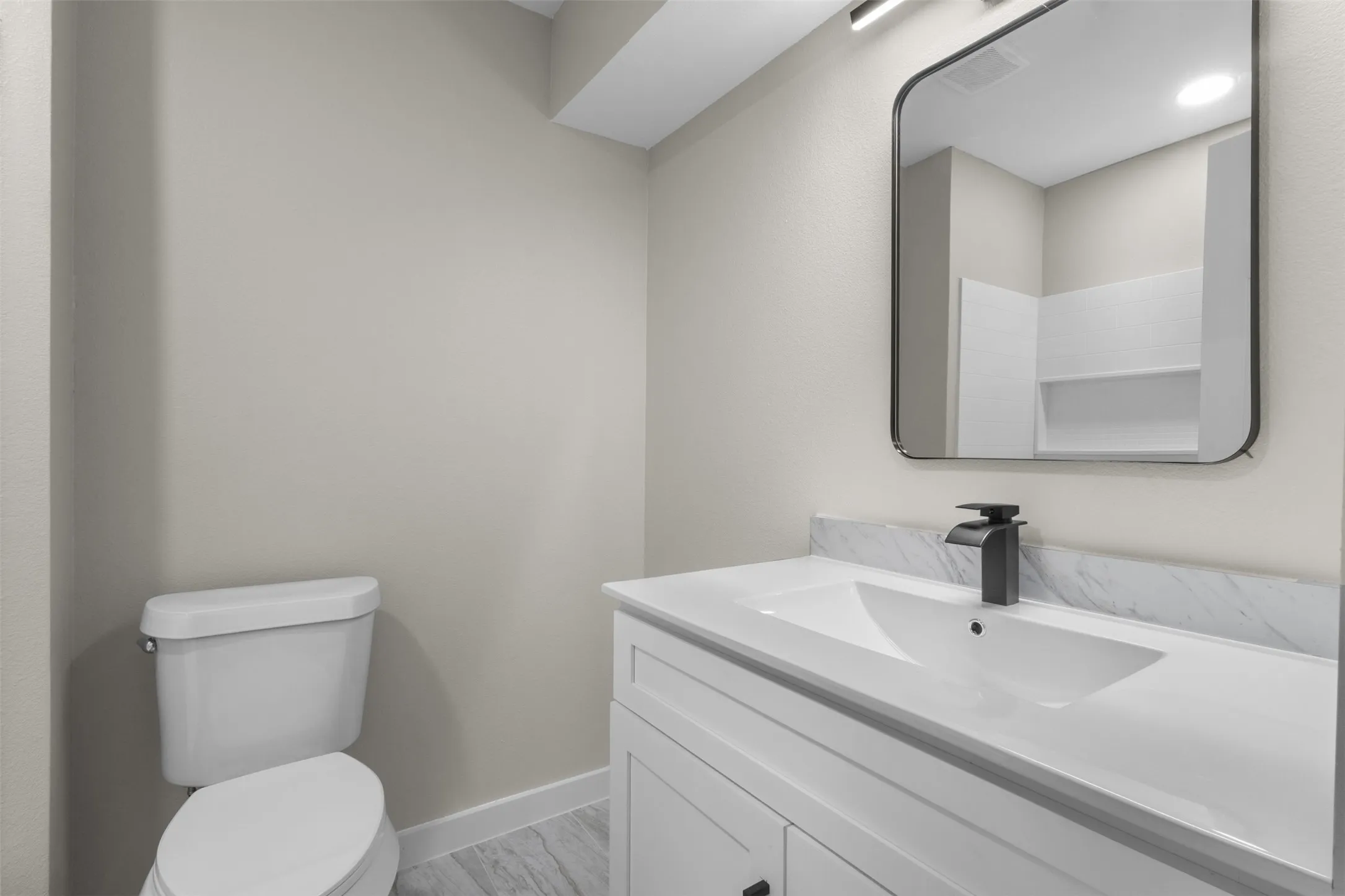 Modern bathroom featuring a white vanity with an integrated rectangular sink, quartz countertop, and matte black wall-mounted faucet