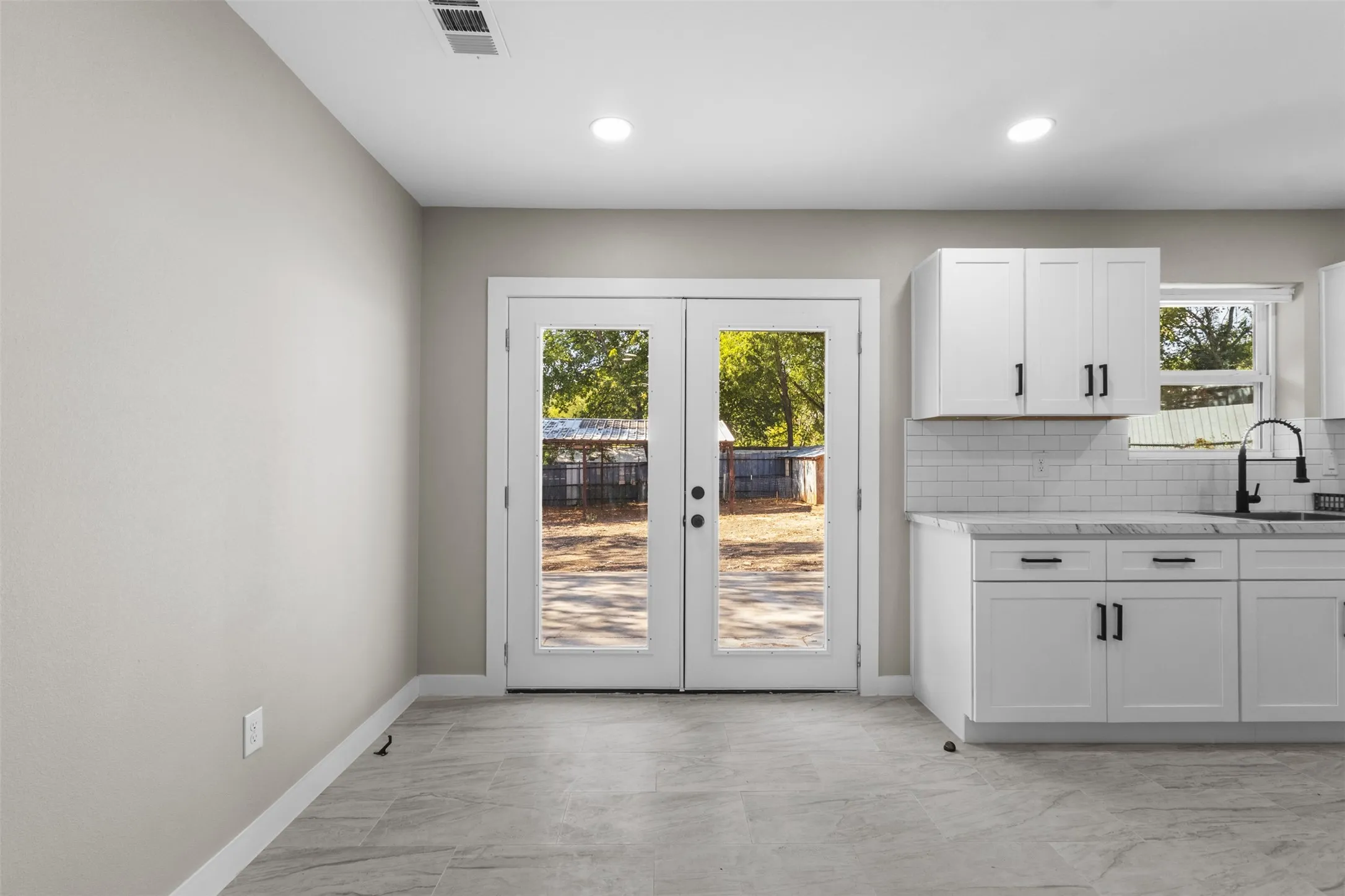 White shaker-style cabinetry with matte black hardware, subway tile backsplash, and light-toned countertops