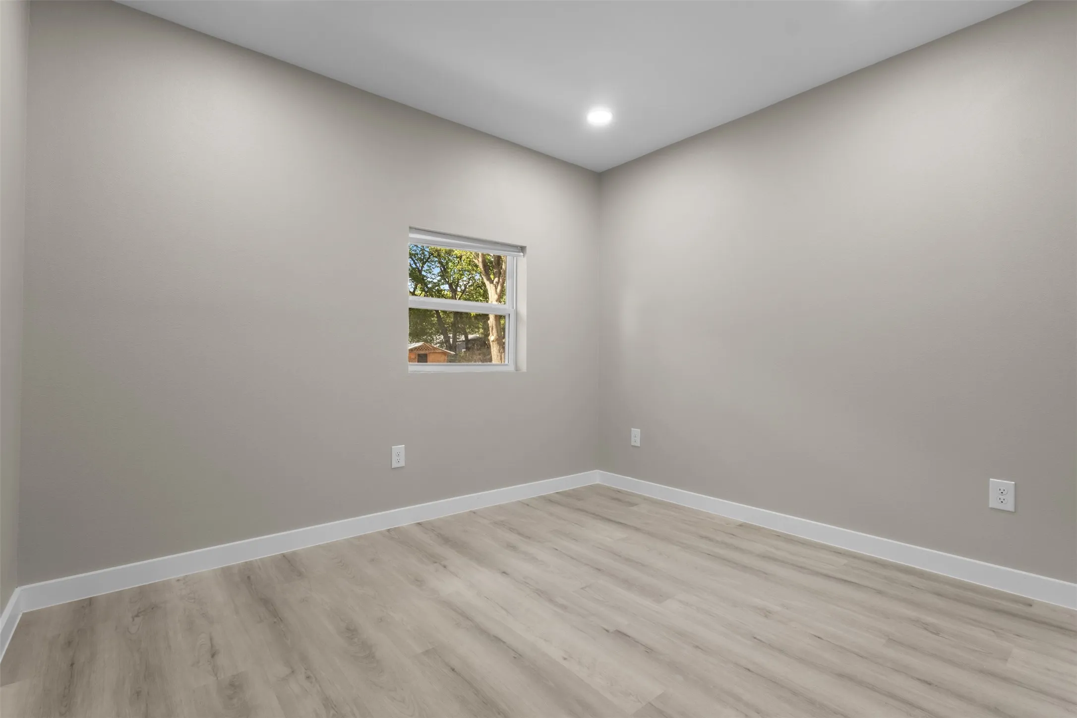 Recessed ceiling lighting, light gray wall finish, wood-finish flooring, white window trim, and white baseboards