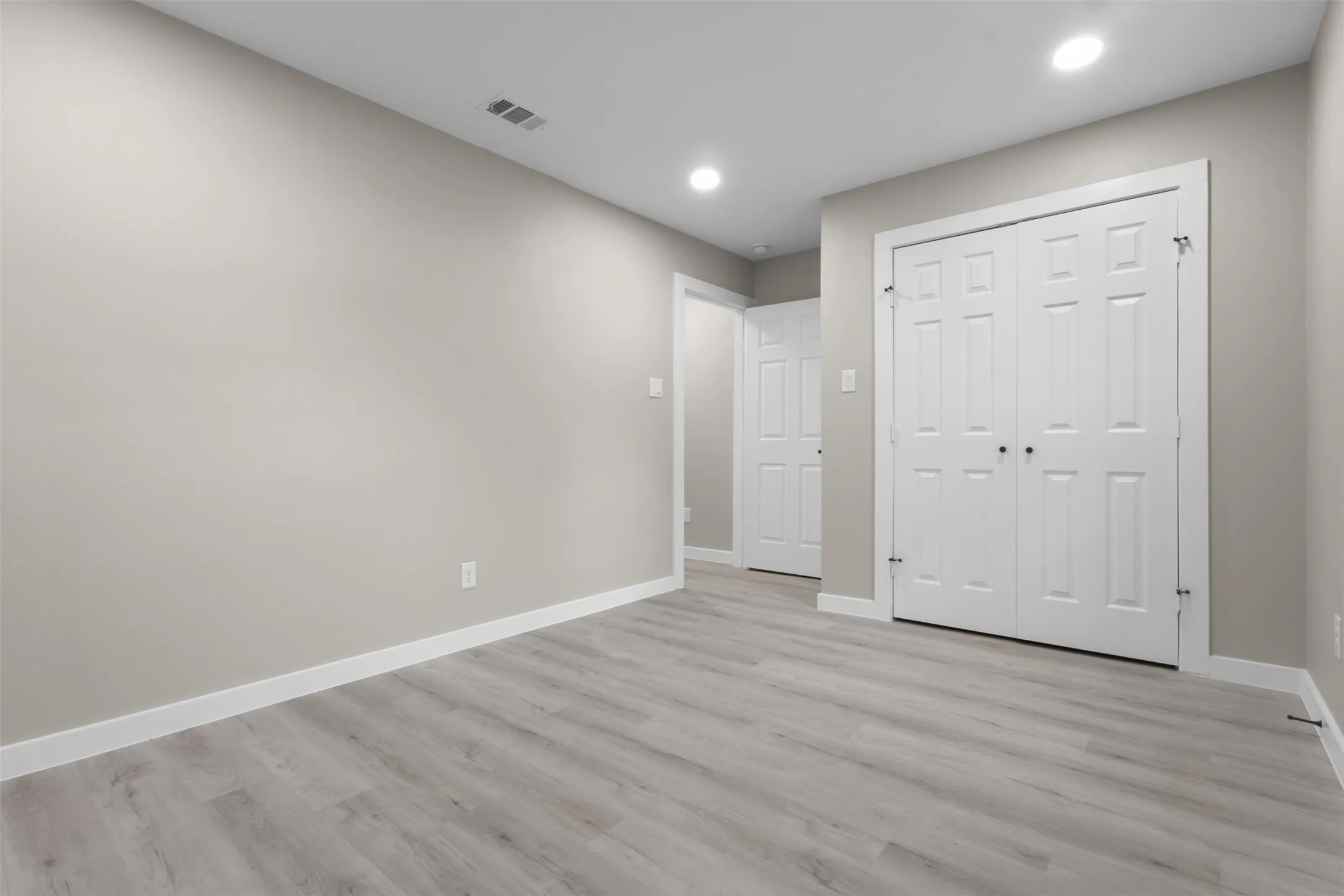 Recessed lighting, light gray walls, wood-finish flooring, white trim, and paneled doors