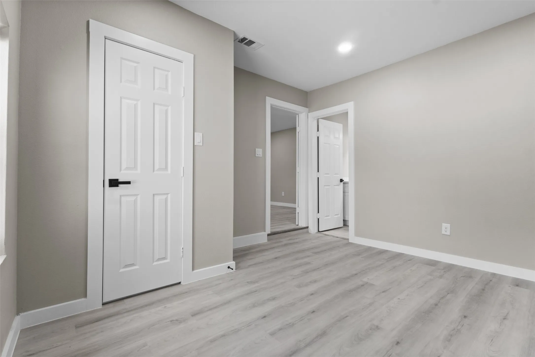 Light gray wood-finish flooring, recessed ceiling lighting, and crisp white trim