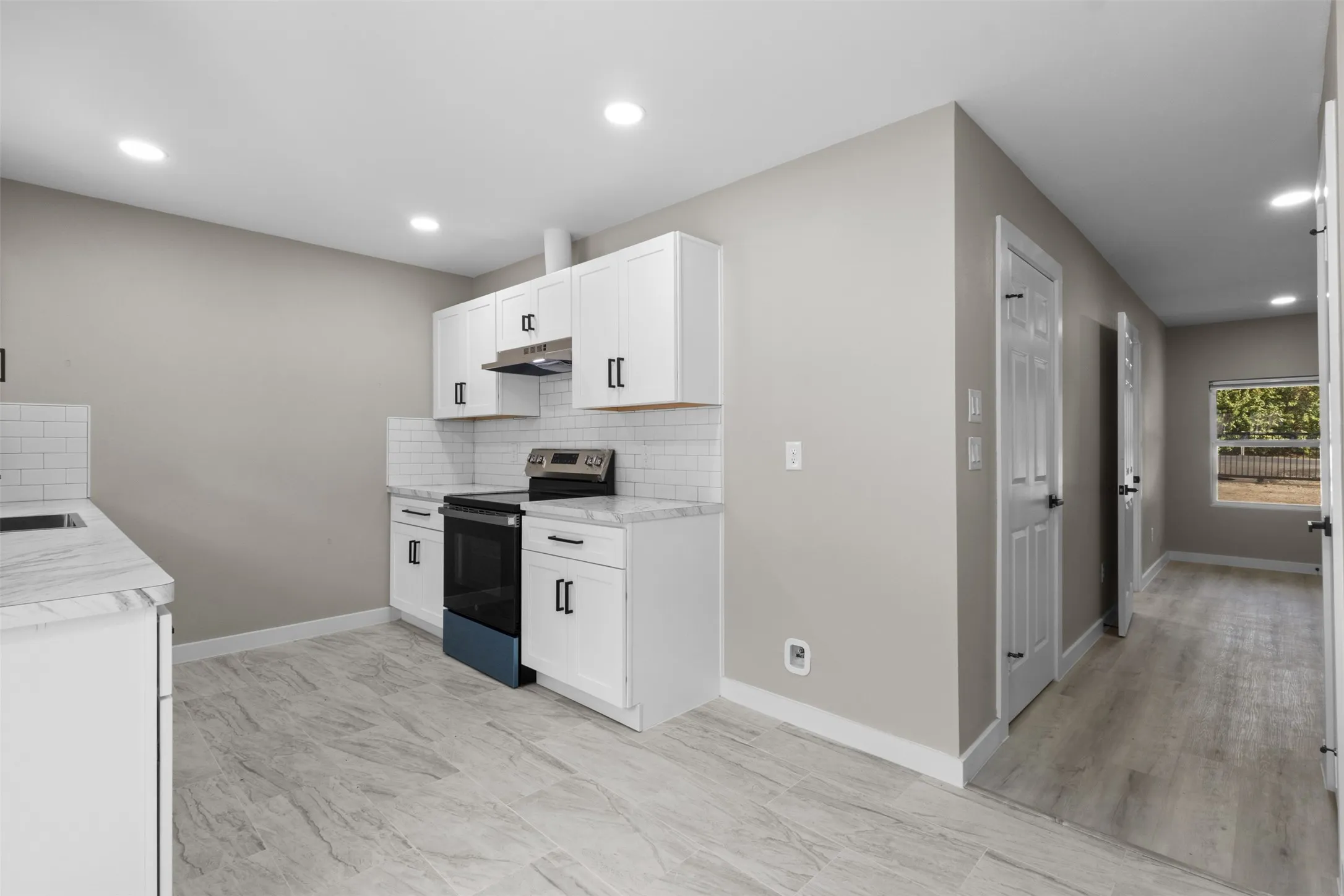 Kitchen featuring white shaker cabinetry, subway tile backsplash, recessed lighting, and wood-finish flooring