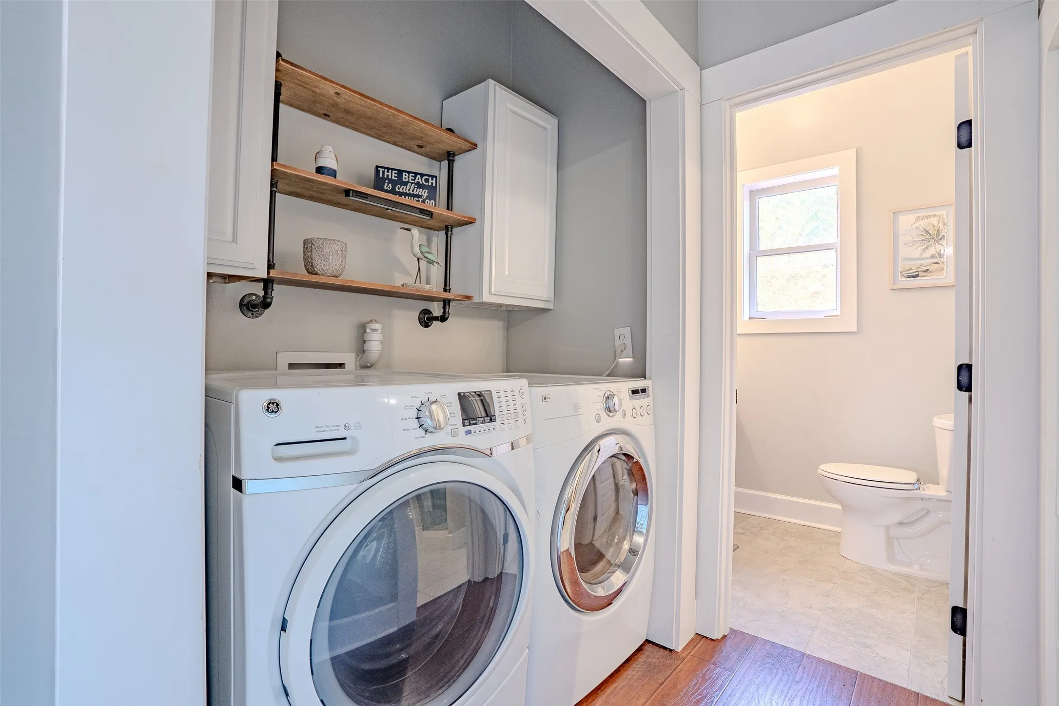 Laundry area with built-in upper cabinetry and industrial-style wood shelving