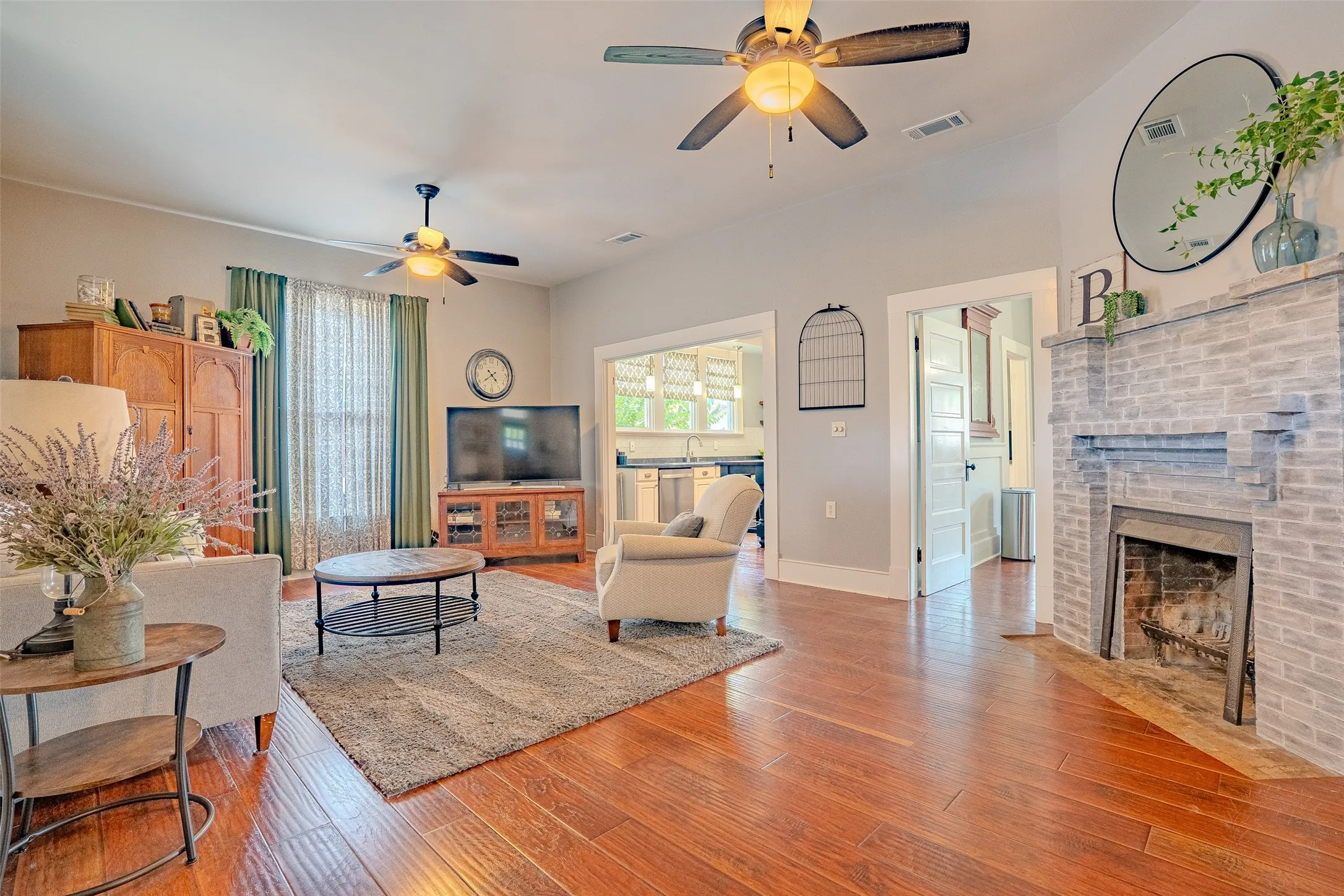 Laminate flooring, two ceiling fans, painted brick fireplace, and cased openings