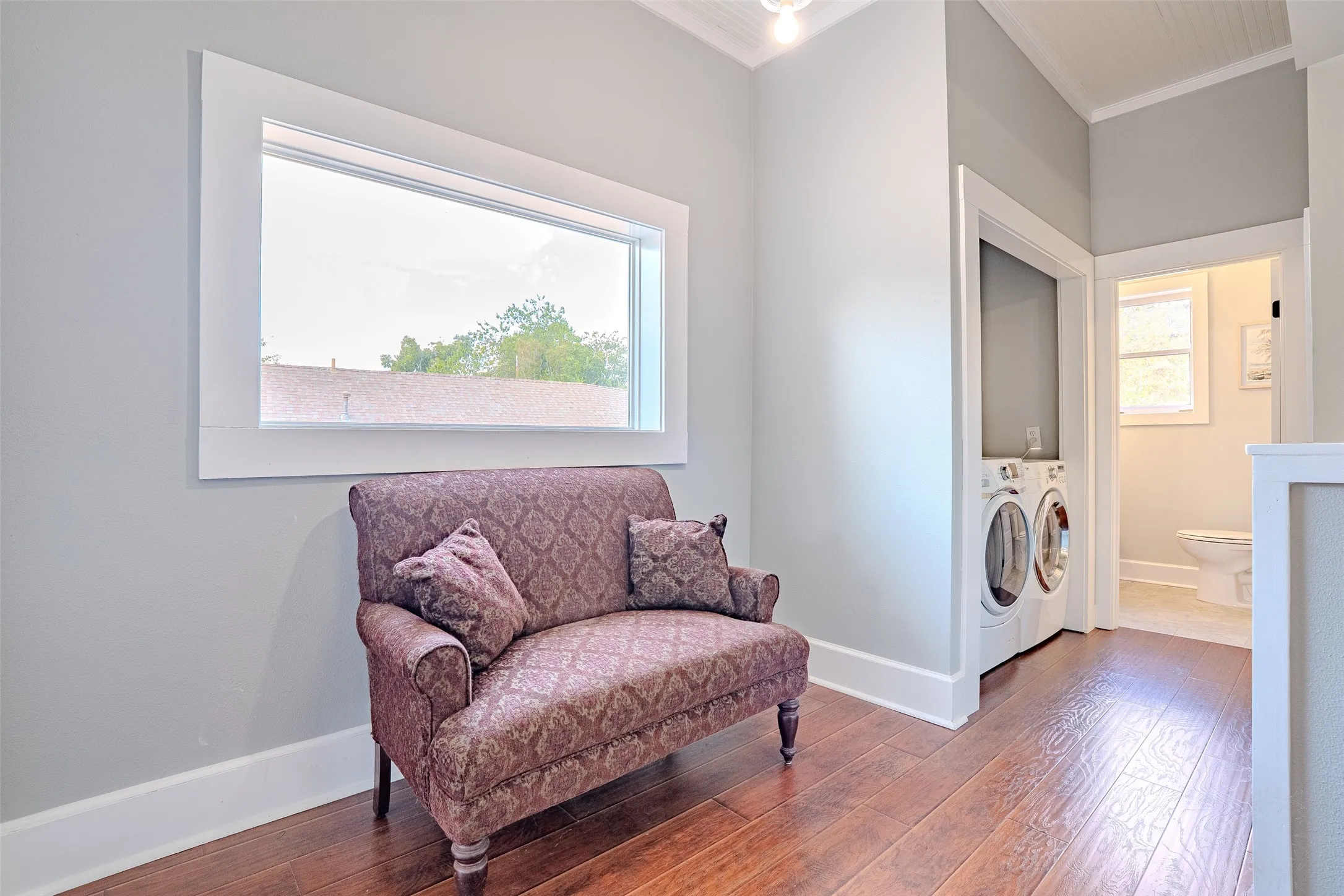 Laminate flooring, white trim, laundry appliances, and a window