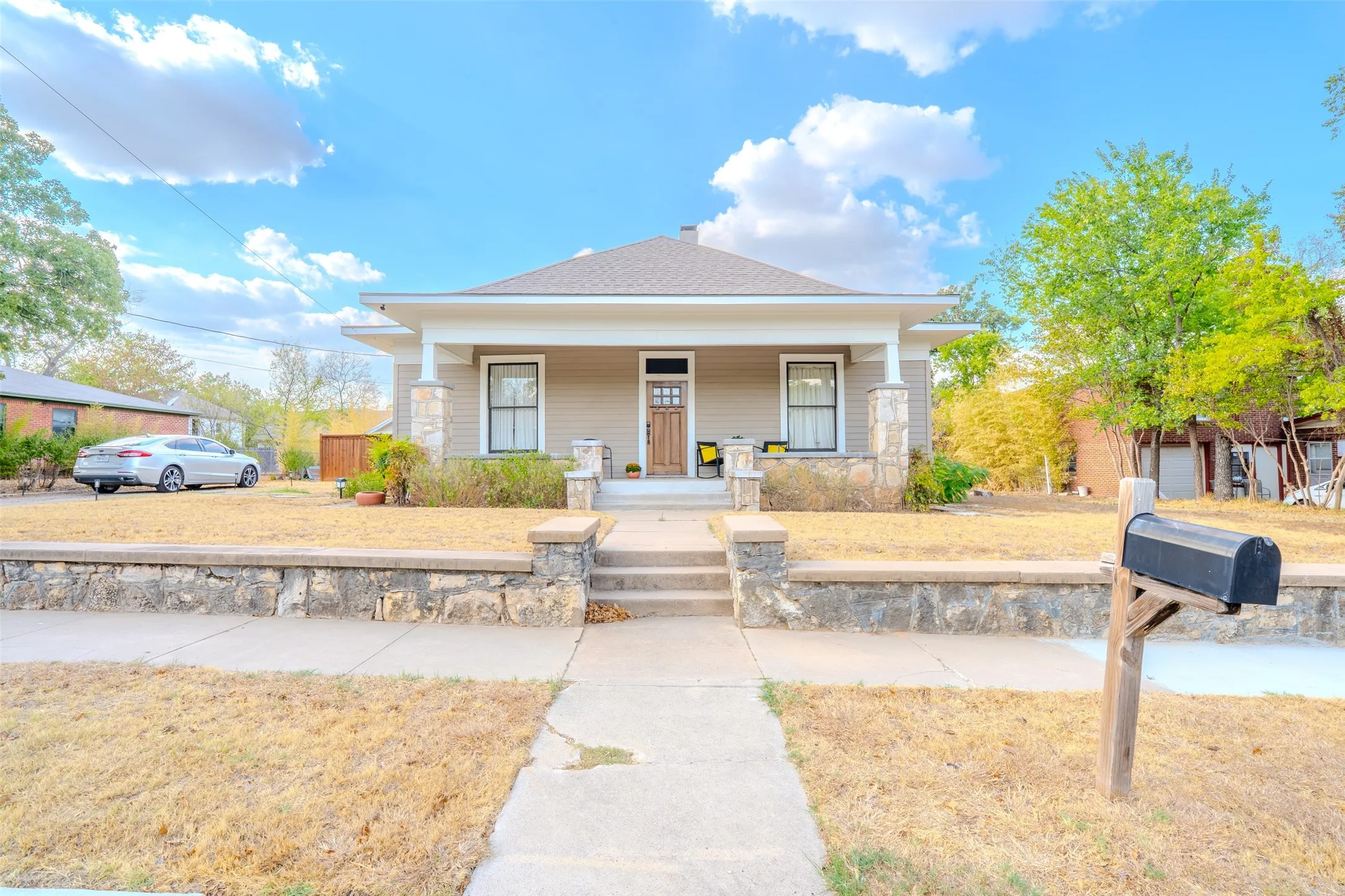 Craftsman-style exterior with a covered porch, stone-clad columns, and a multi-panel front door