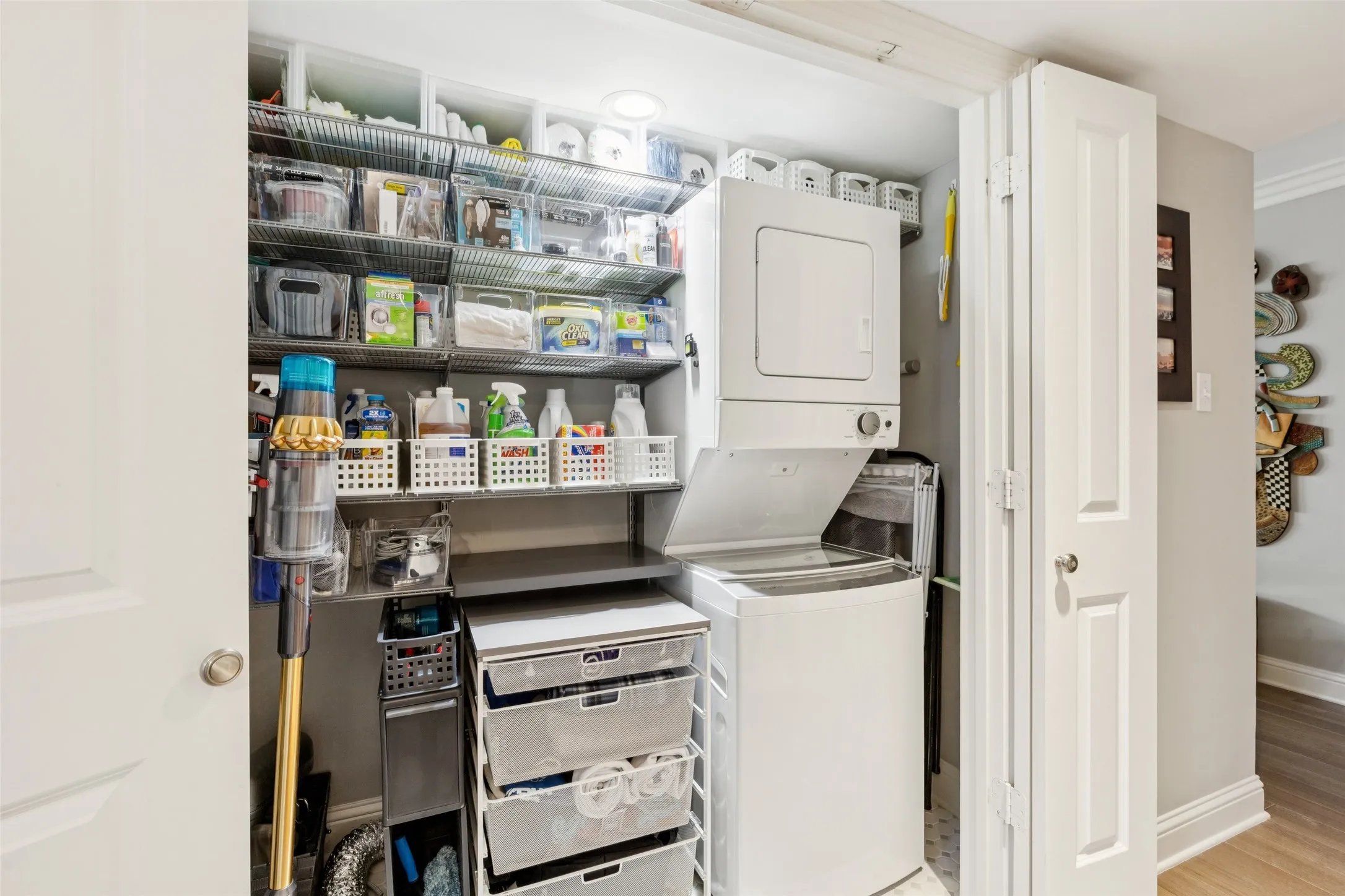 Built-in stacked washer and dryer, custom shelving system, recessed ceiling light, and panel doors