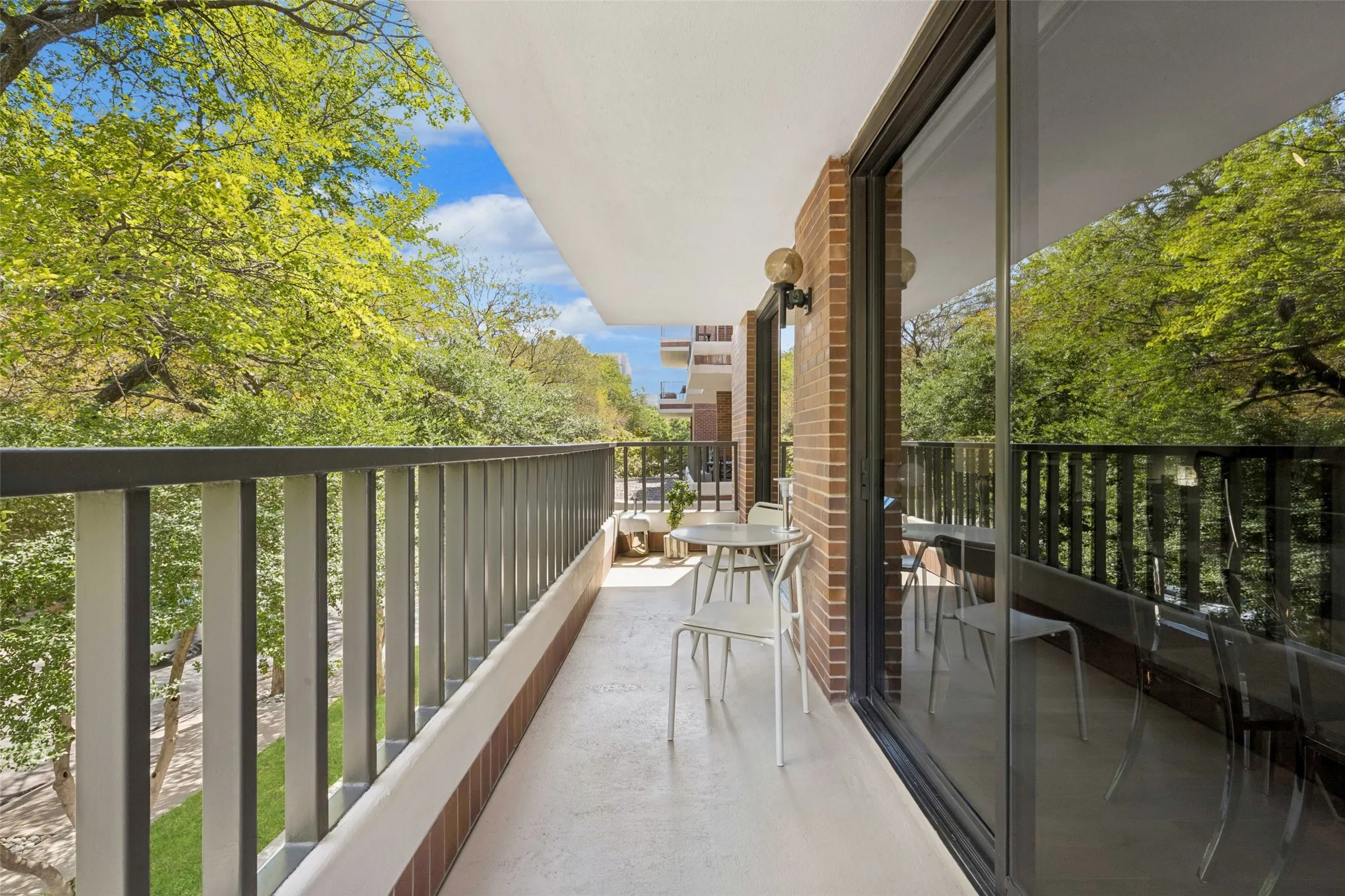 Private balcony with a metal railing and a brick exterior wall