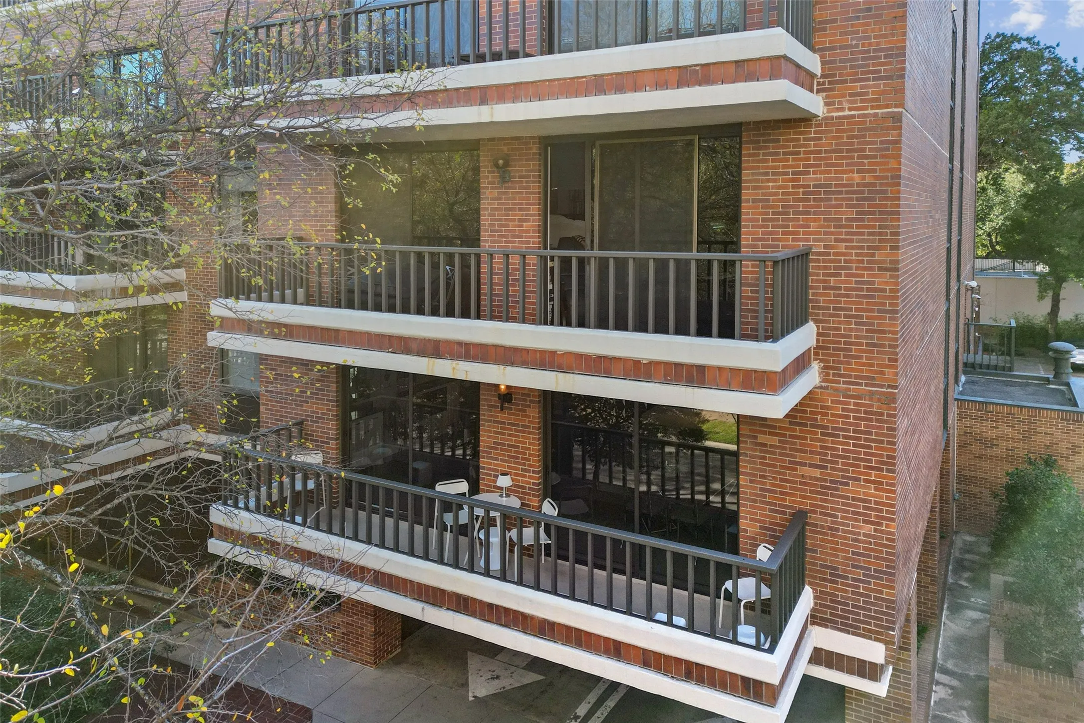 Brick exterior with multiple private balconies featuring dark railings and white trim