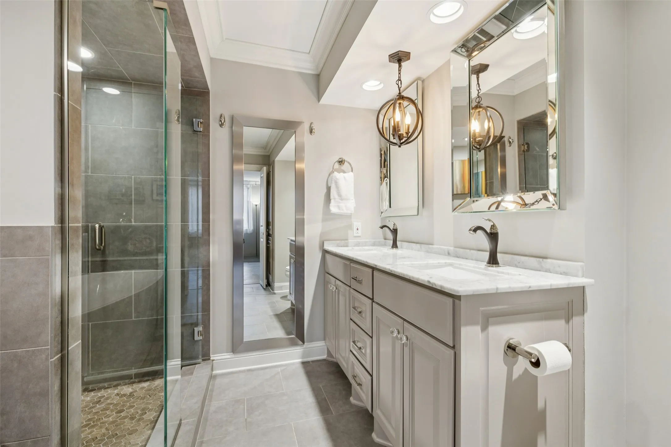 Dual vanity with stone countertop and integrated sinks, individual framed mirrors, and pendant lighting