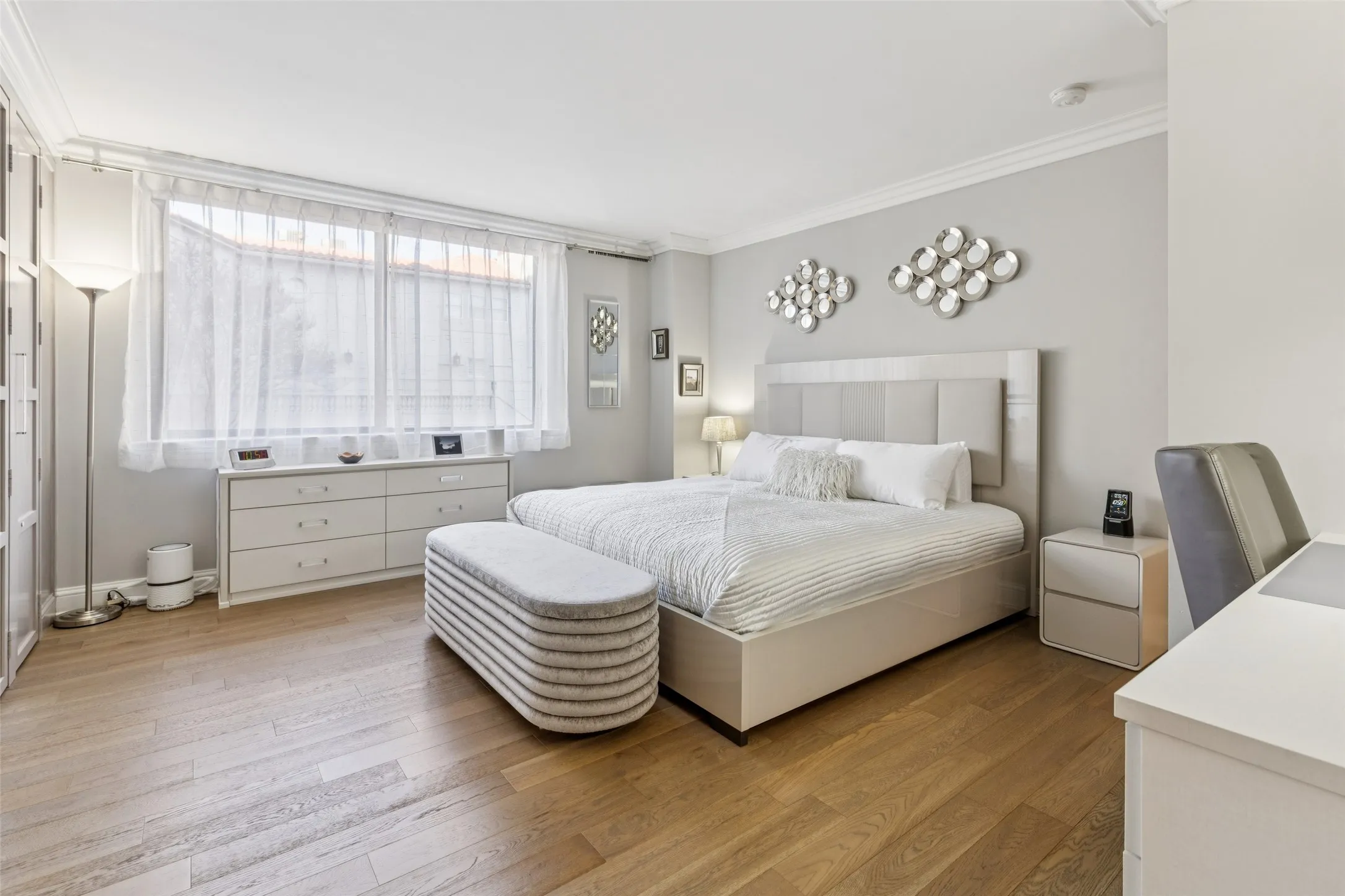 Wood-finish flooring with a wide window, built-in storage, and crown molding