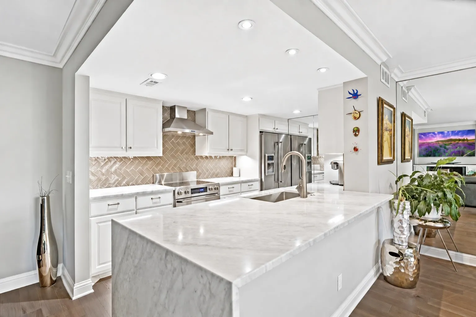 Kitchen with white marble waterfall counters.