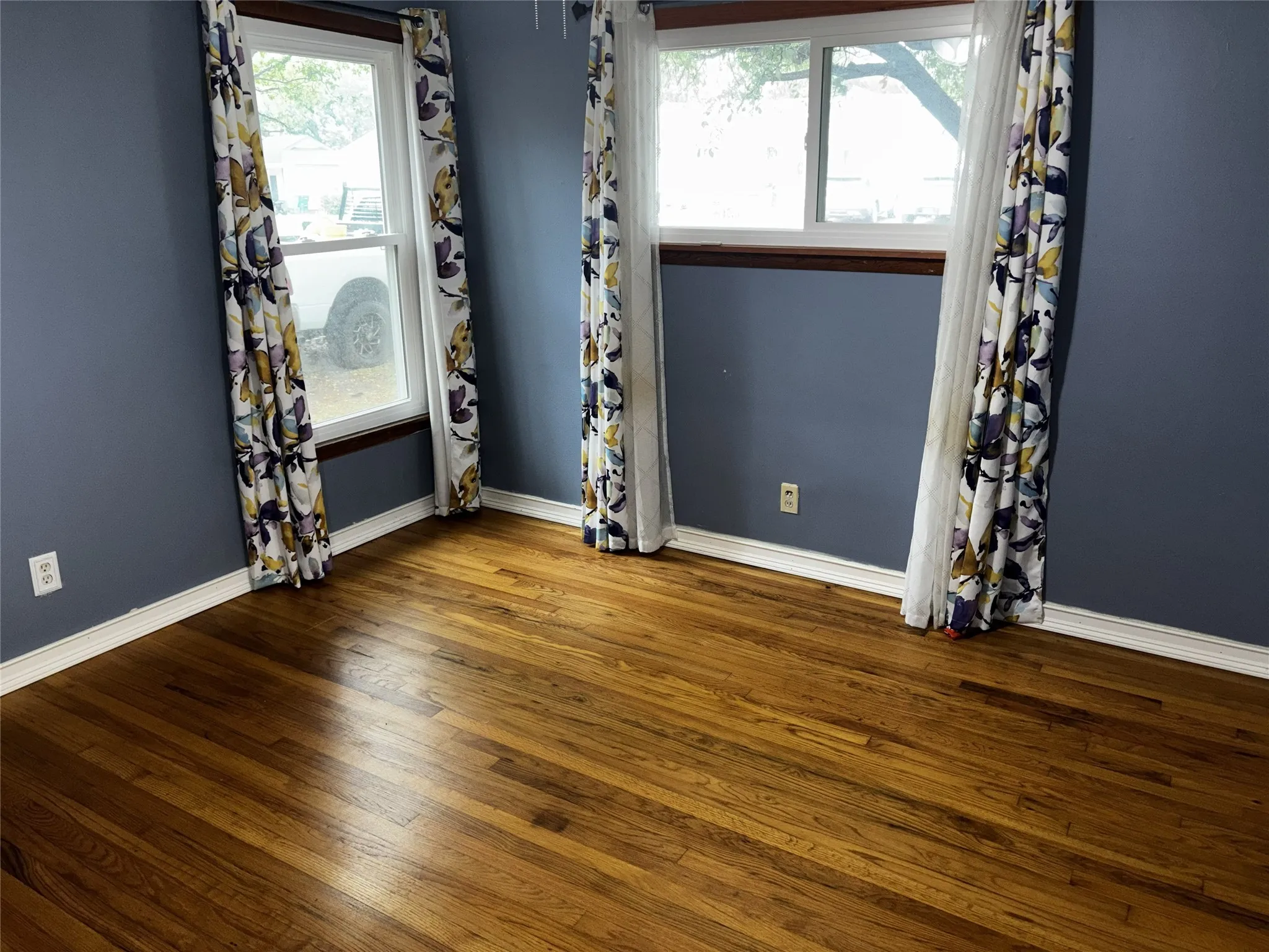 Hardwood flooring, painted walls, two windows, and white trim