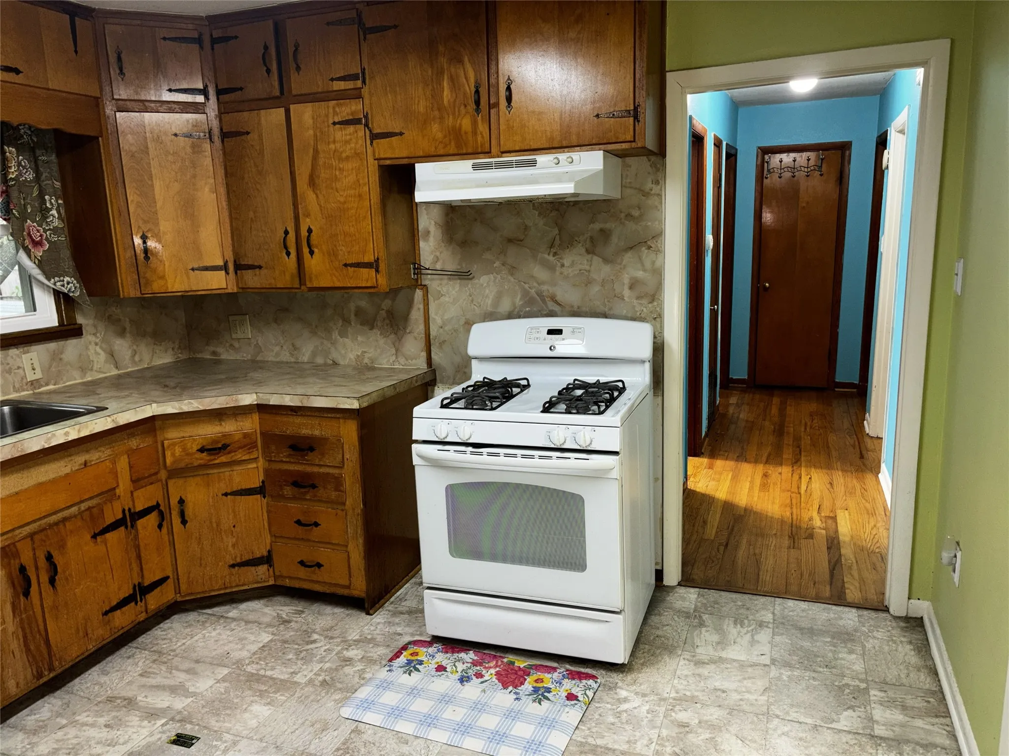 Kitchen featuring wood cabinetry, laminate countertops, and a gas range