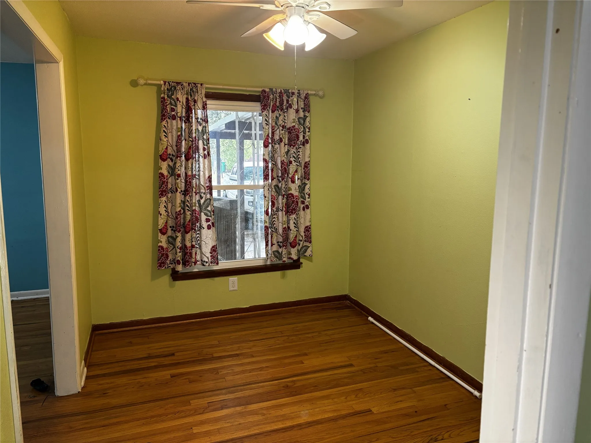 Wood-finish flooring with a ceiling fan, a window, and painted walls