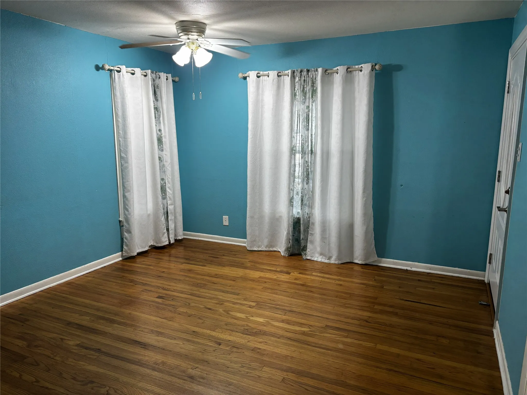 Hardwood flooring, ceiling fan, and white trim