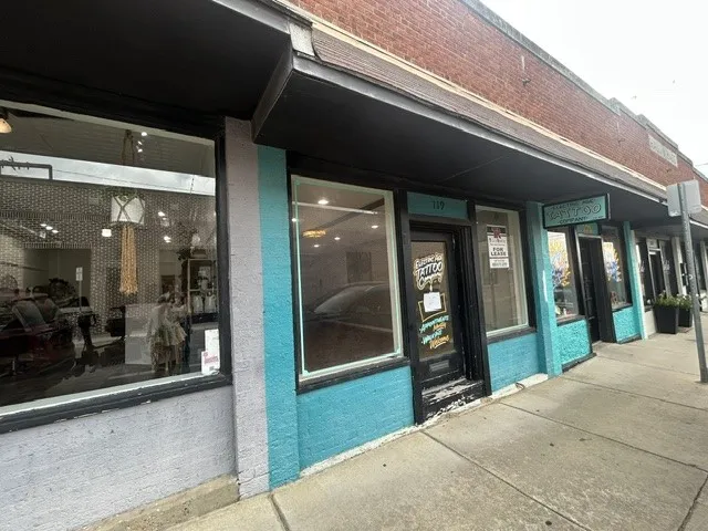 Storefront featuring brick and stucco exterior, large display windows, and a prominent awning