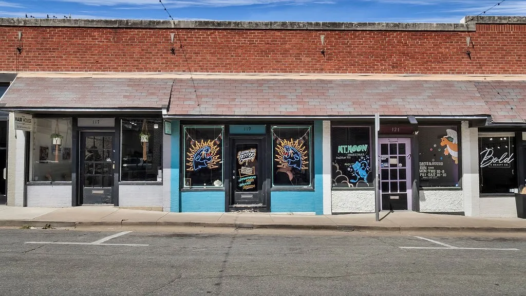 Brick facade with multiple storefronts, each featuring large display windows and individual entry doors