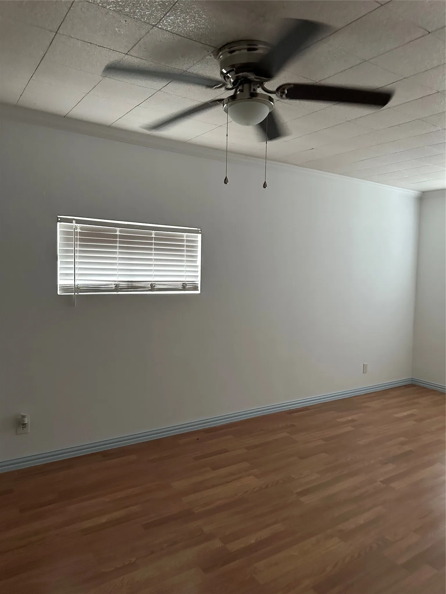 Wood-finish flooring, white walls, and a ceiling fan with integrated lighting