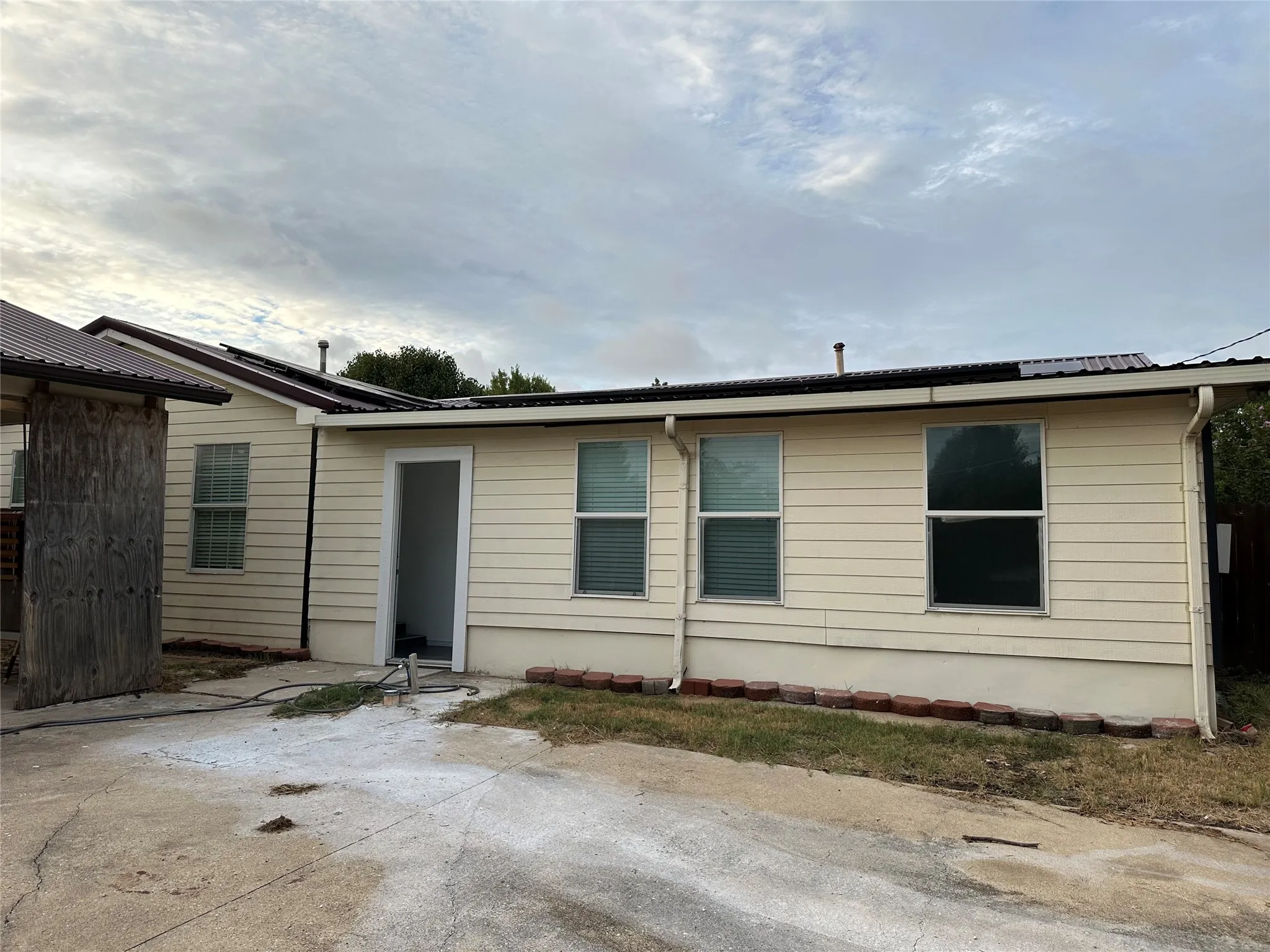 Light-colored horizontal siding, multiple windows, and a metal roof